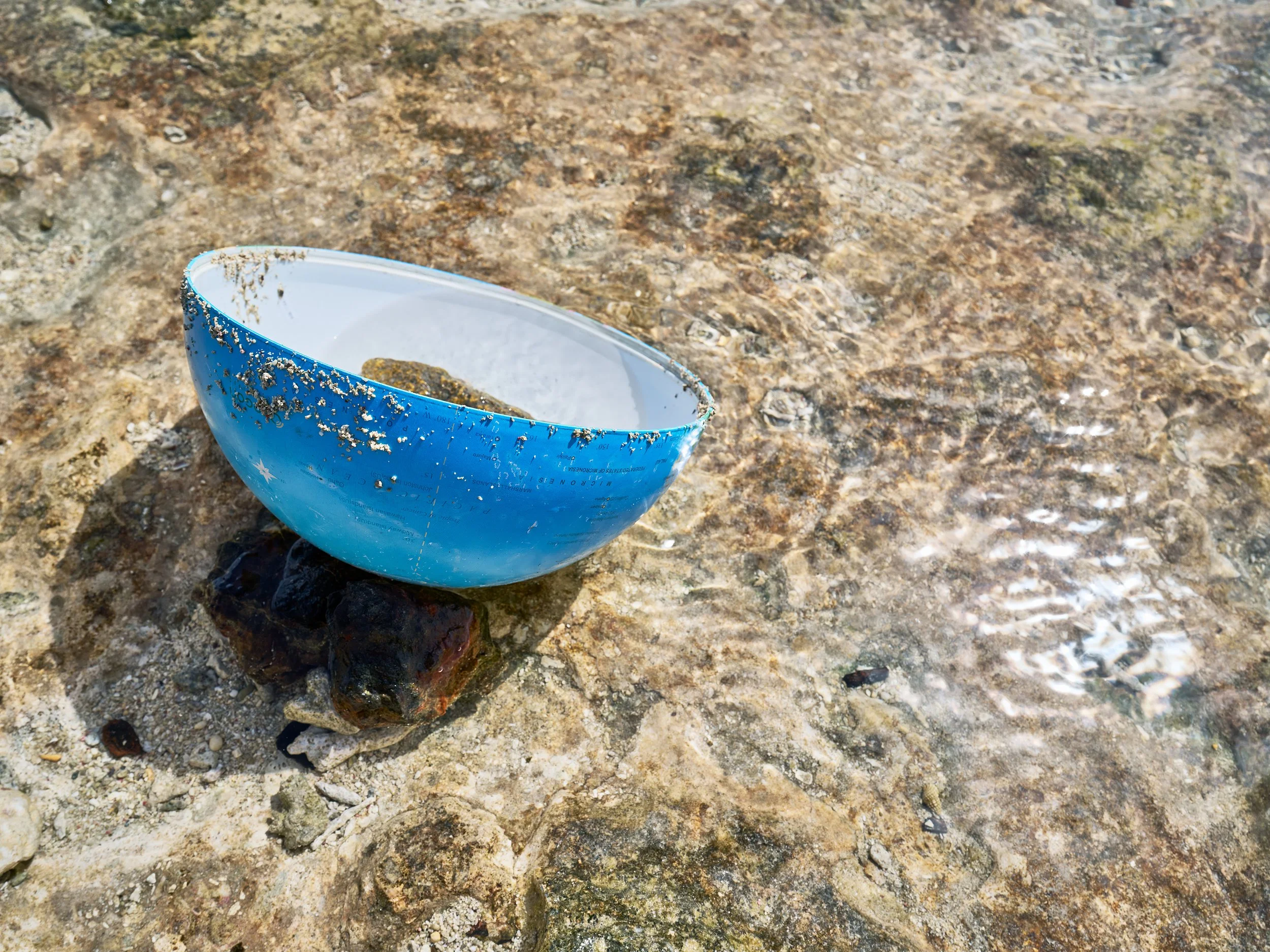  The northern hemisphere of a globe found in the tidal zone on Majuro, with the Marshall Islands appearing just above the water line. 
