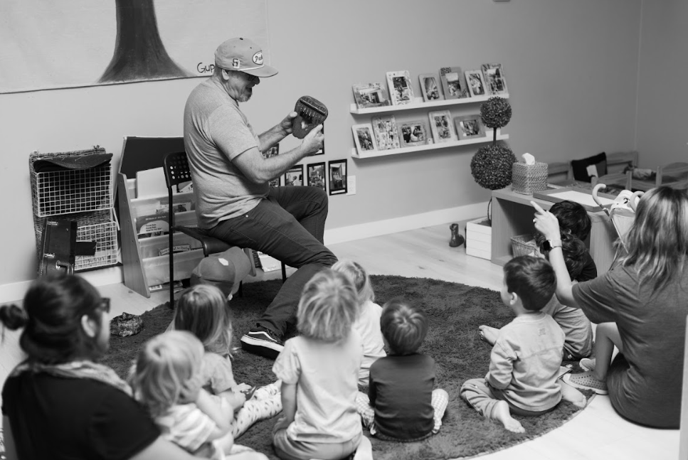 Mr Troy playing music for a group of preschoolers in a Kids By The Sea classroom.