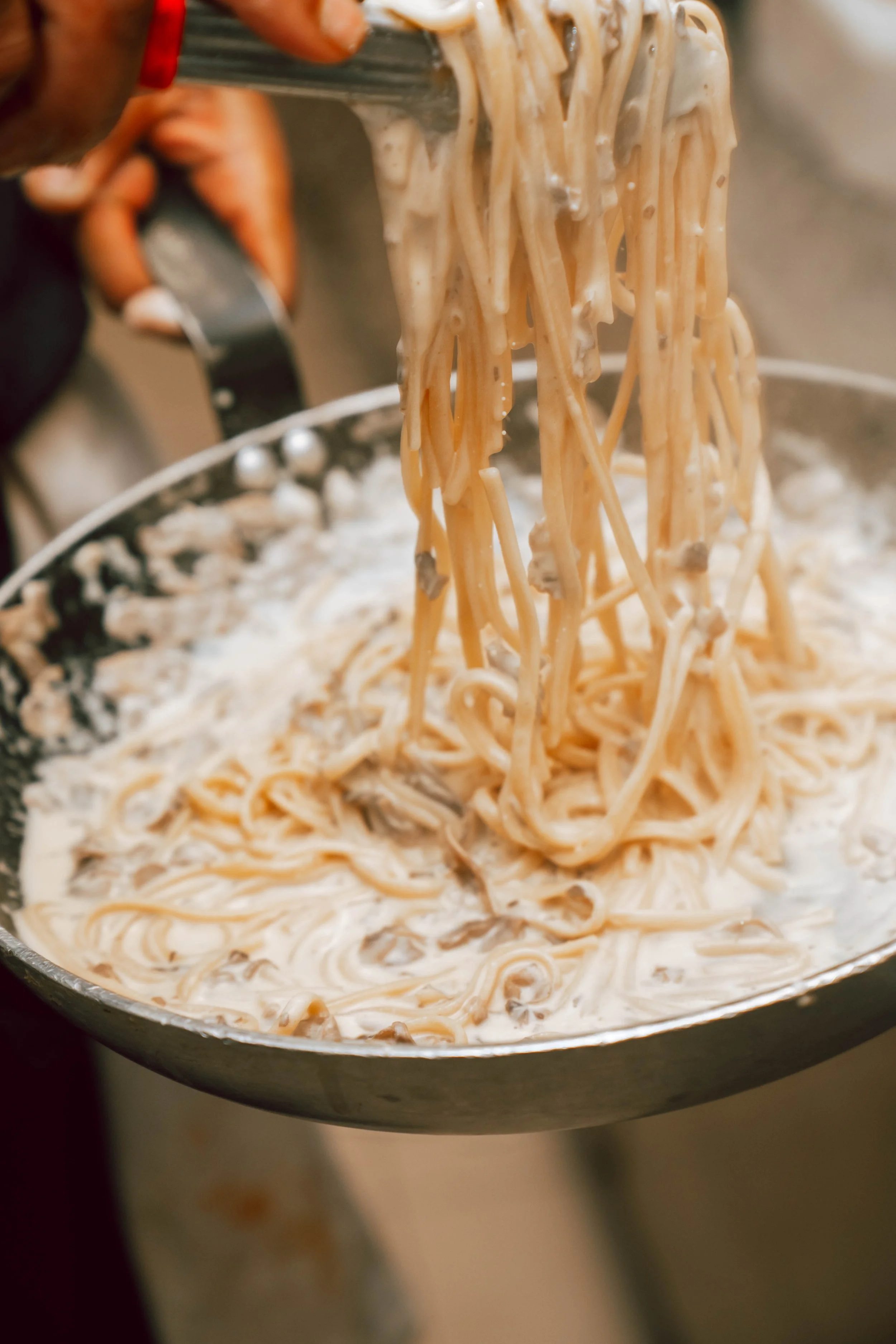 Cuisses de pâtes avec sauce aux champignons dans une poêle.