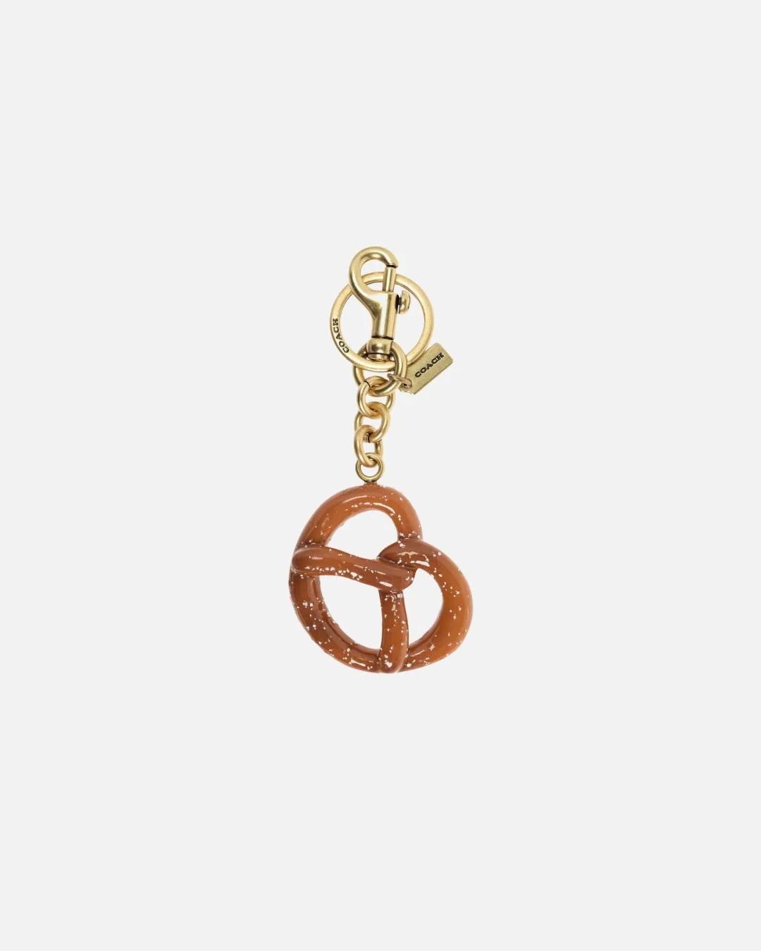 Twist, charm, repeat. 🥨✨
This @coach  pretzel bag charm turns an everyday snack into a playful luxury accessory. Crafted with the brand&rsquo;s signature attention to detail, it adds a touch of humor and personality to your favorite bag. Quirky, nos