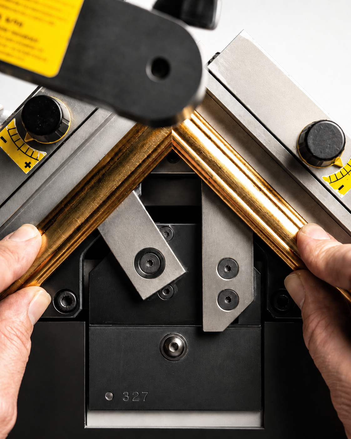 Close-up of a precision engineering process with hands holding a copper component between machinery parts.