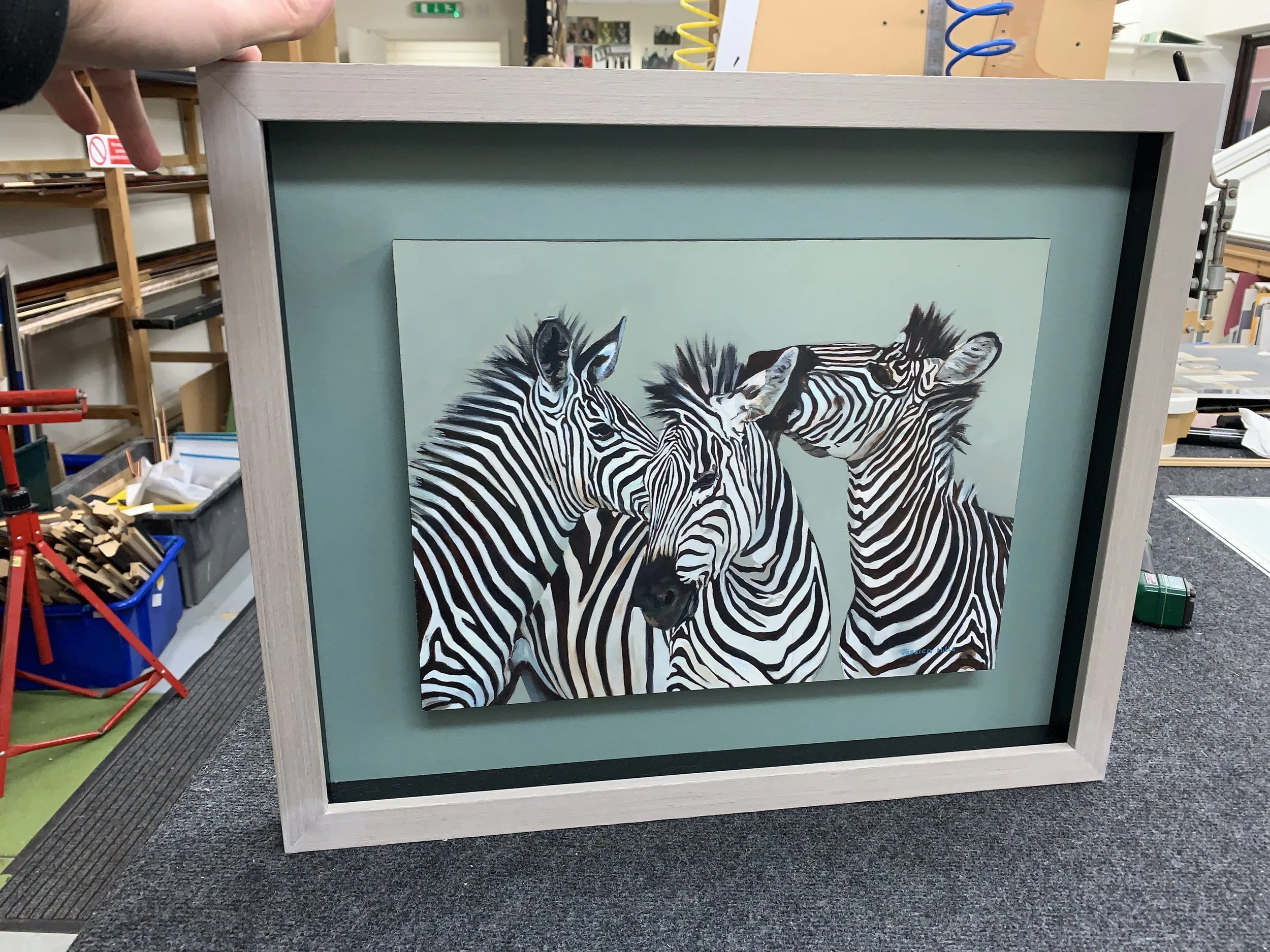 Painting of two zebras with black and white stripes on a canvas in an art studio.