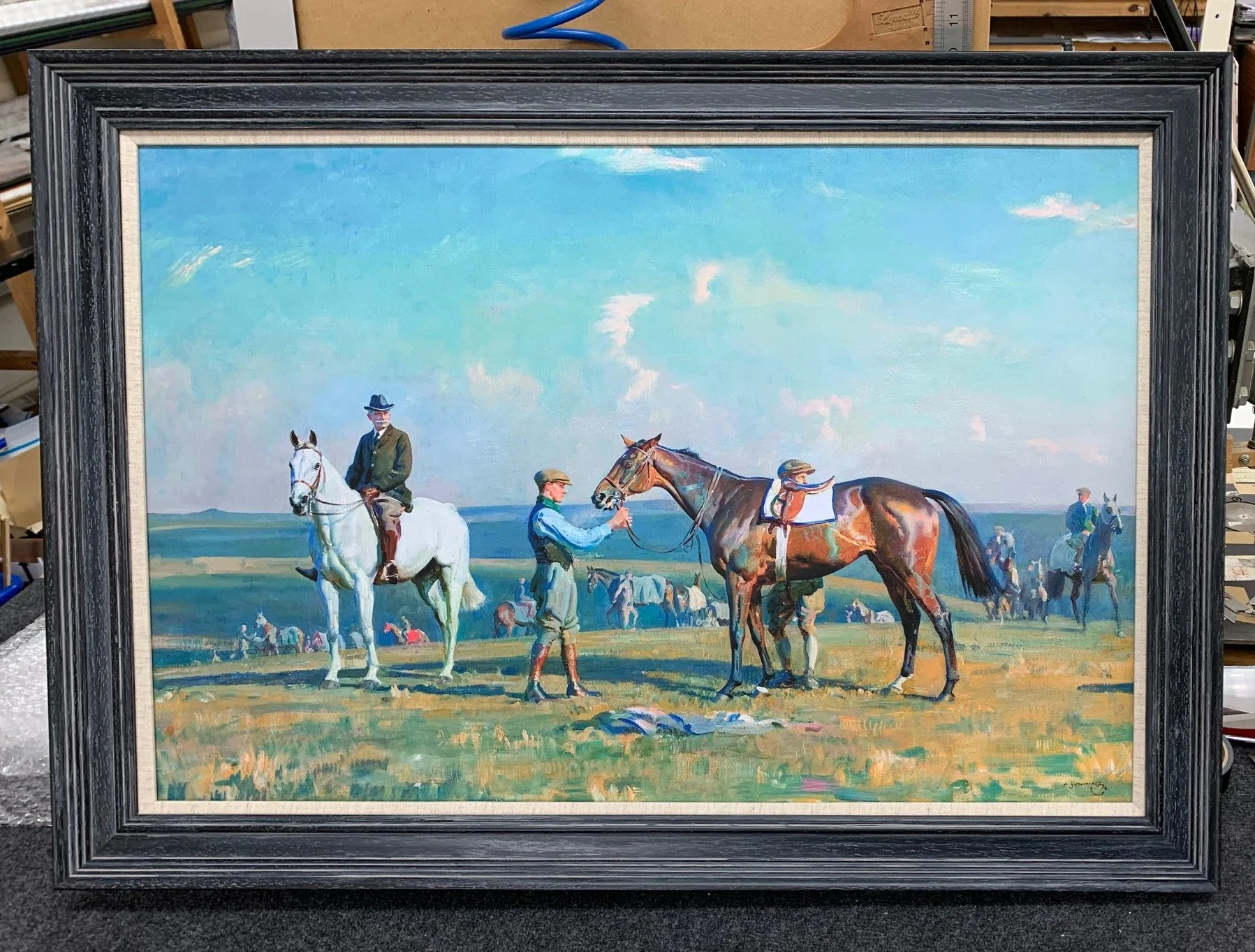 A painting of people and horses in a grassy field under a bright blue sky with some clouds. Several riders are on horseback, and a few people are standing, holding or tending to horses.
