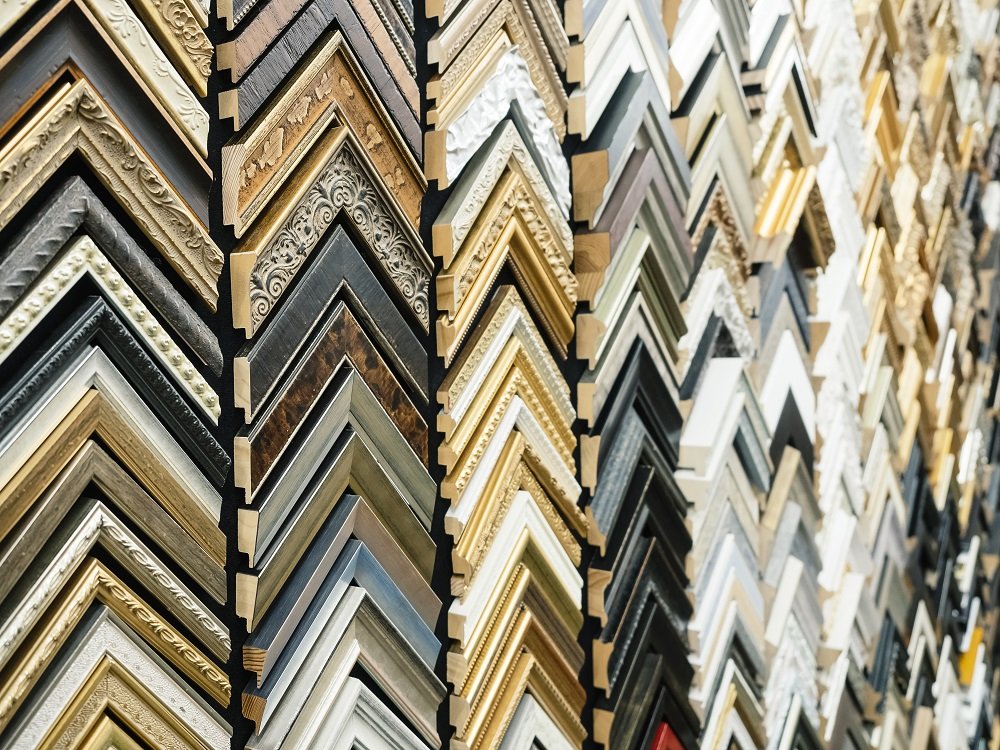 A display of assorted picture frame samples in various colors, textures, and styles, organized in vertical rows.