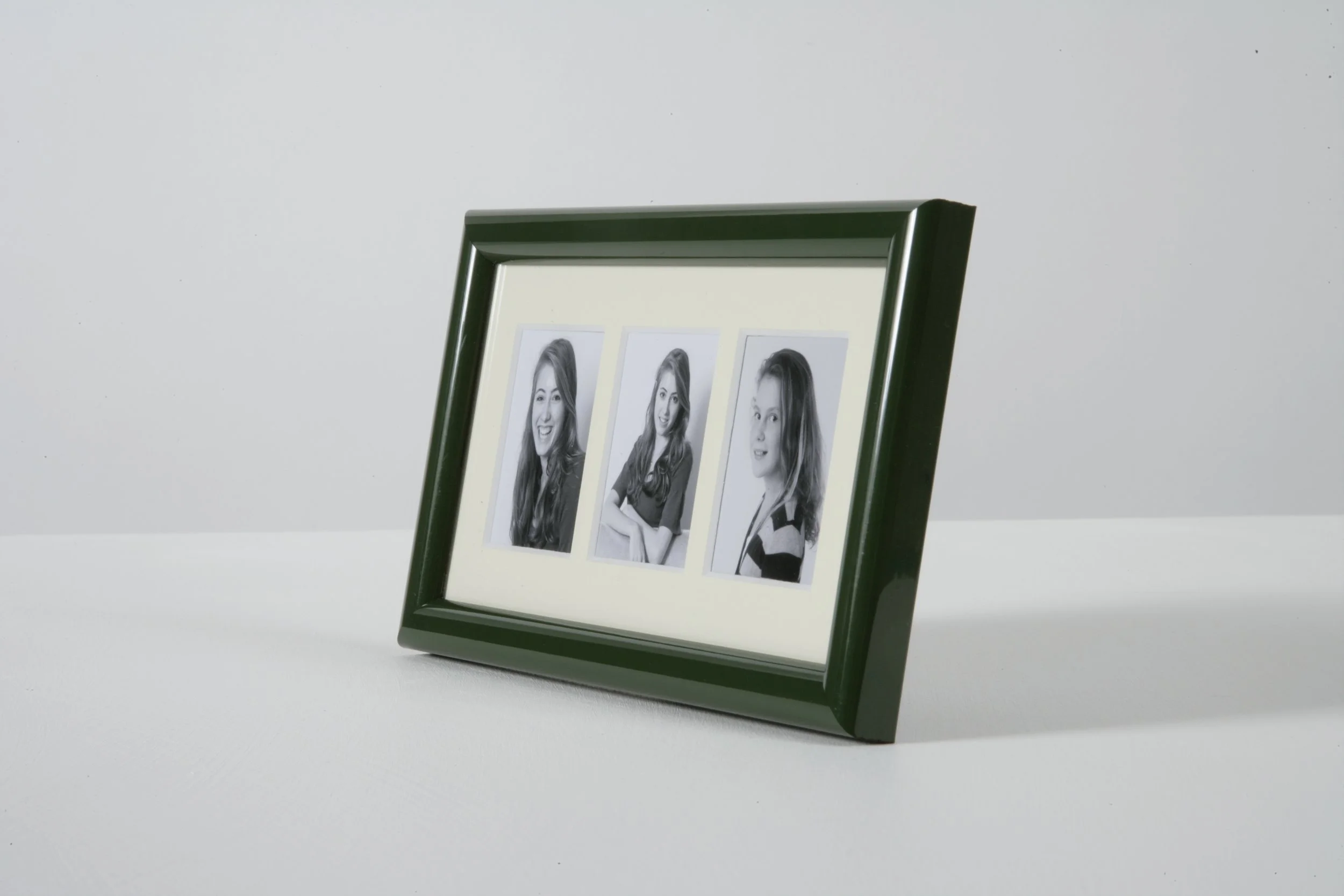 A black-framed photo collage featuring three black-and-white portrait photographs of a young woman with long hair, displayed on a clean, white surface against a plain white wall.