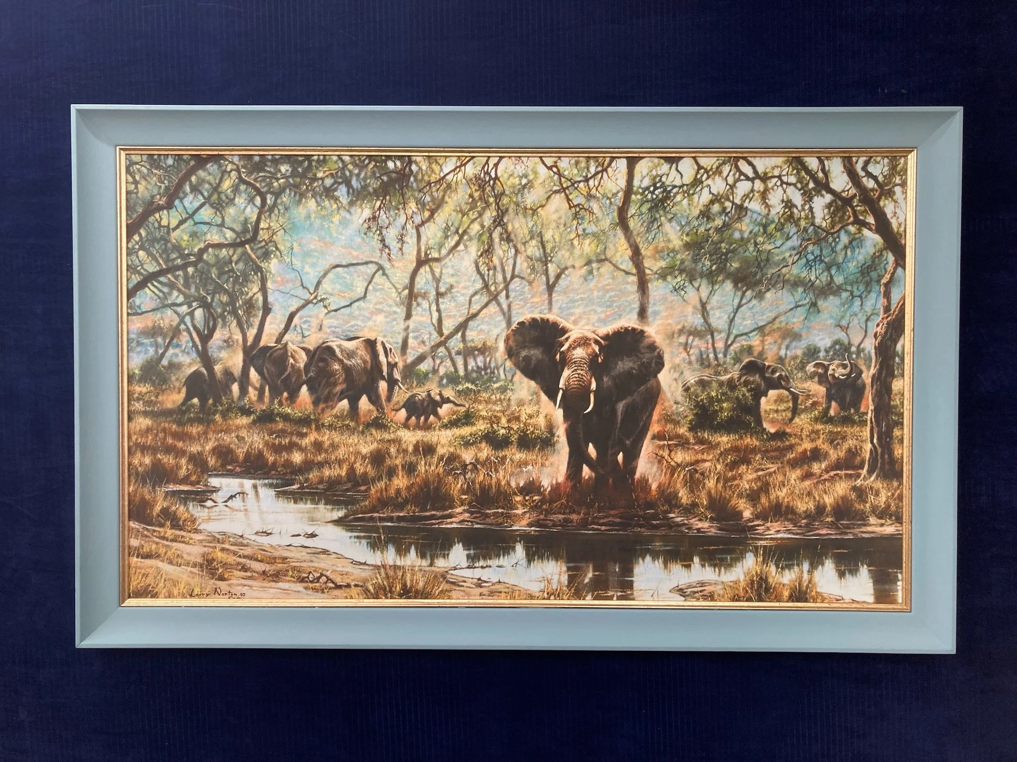 A painting depicting an African savannah scene with elephants and a waterhole, trees with sprawling branches, and a sky with clouds and sunlight filtering through.