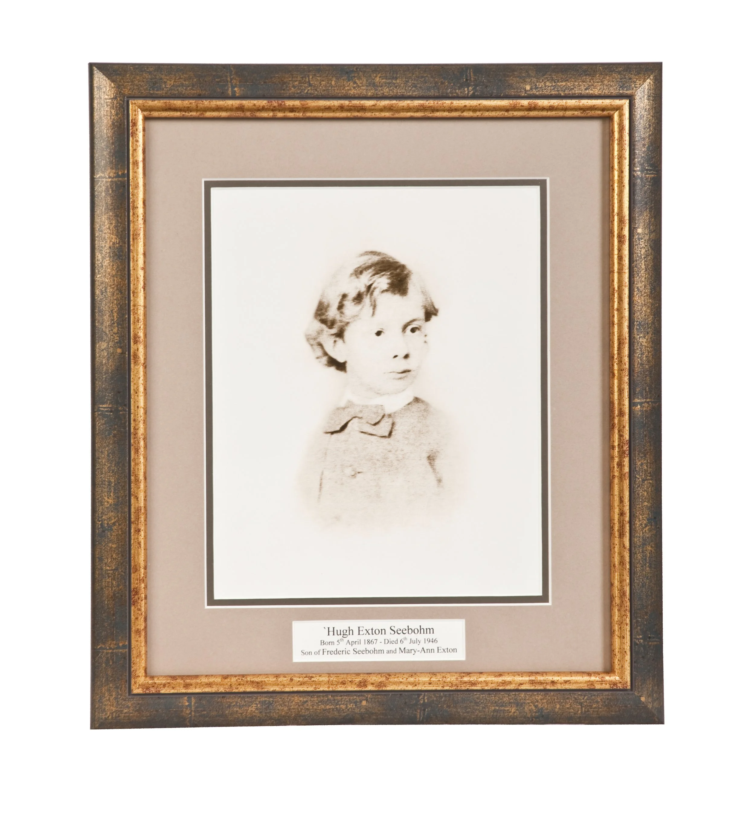 Framed black and white photograph of a young child, Hugh Exton Seebohm, with a label describing his birth and death dates and his parents' names.