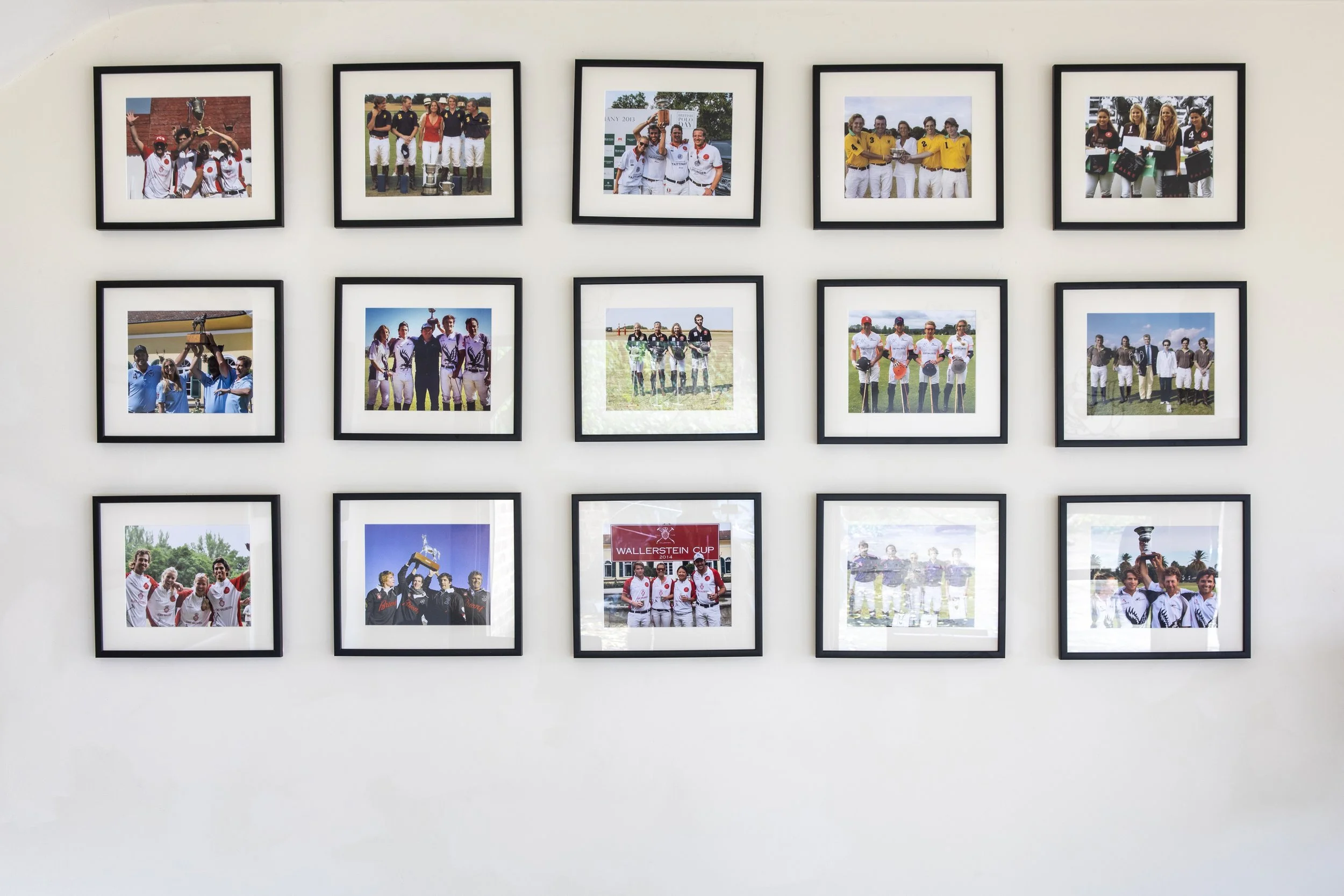 A wall displaying framed photographs of various sports teams and events.