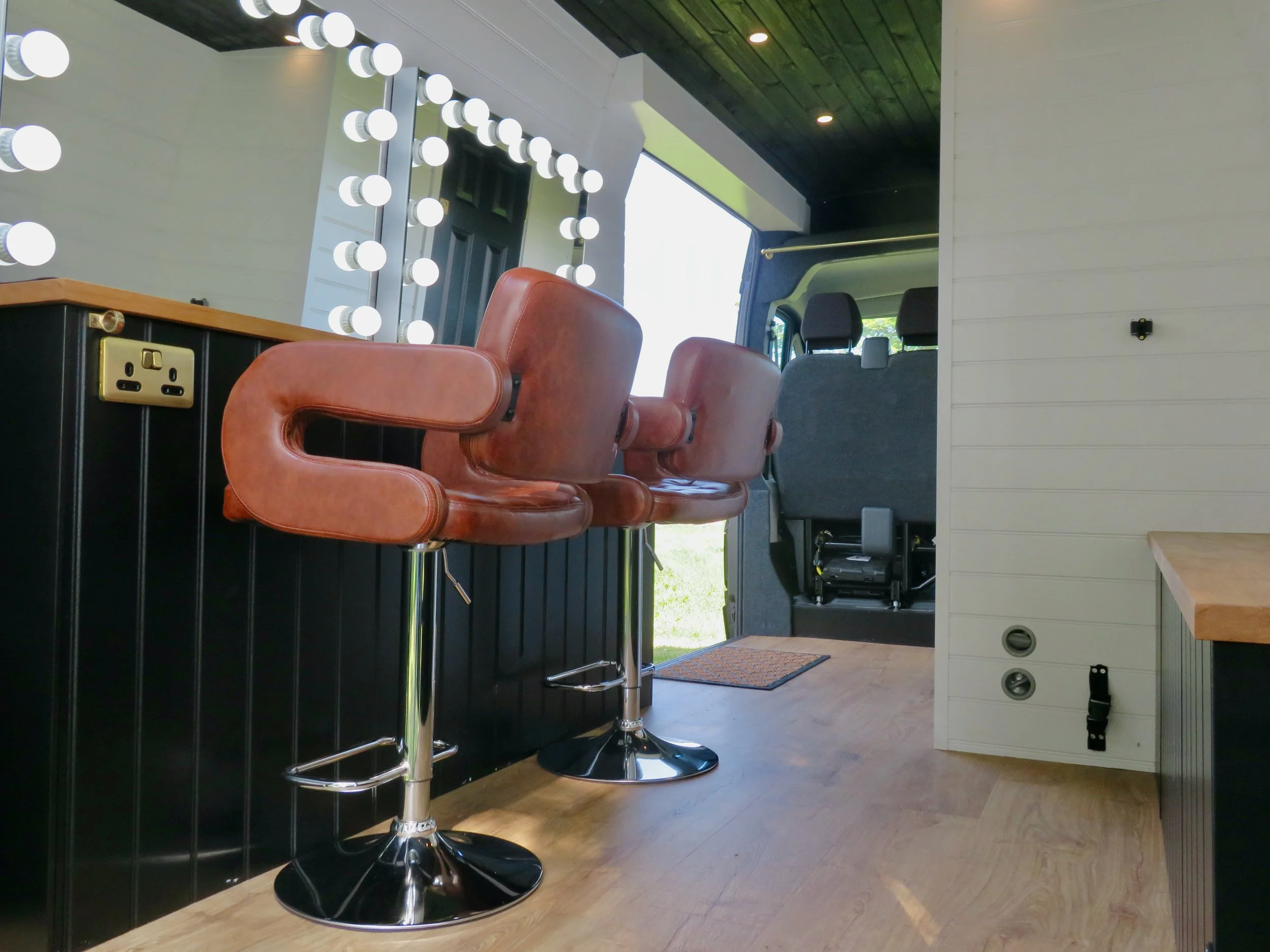Interior of hair and makeup van with brown leather chairs and lvt flooring