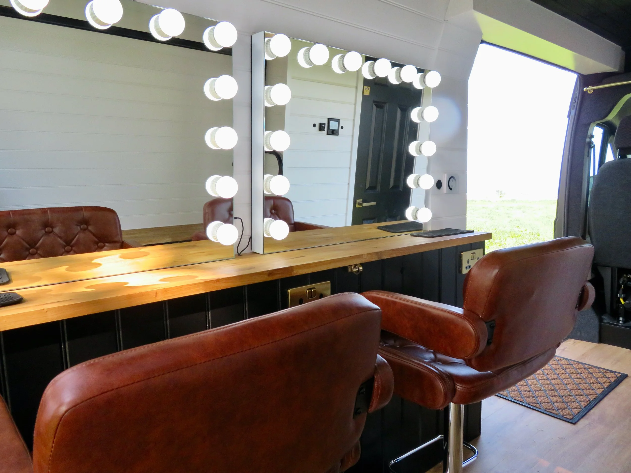 Close up of brown leather hair and makeup chairs with wooden bench and Hollywood mirrors