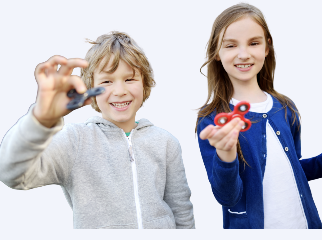 Two children, a boy and a girl, smiling and holding fidget spinners.