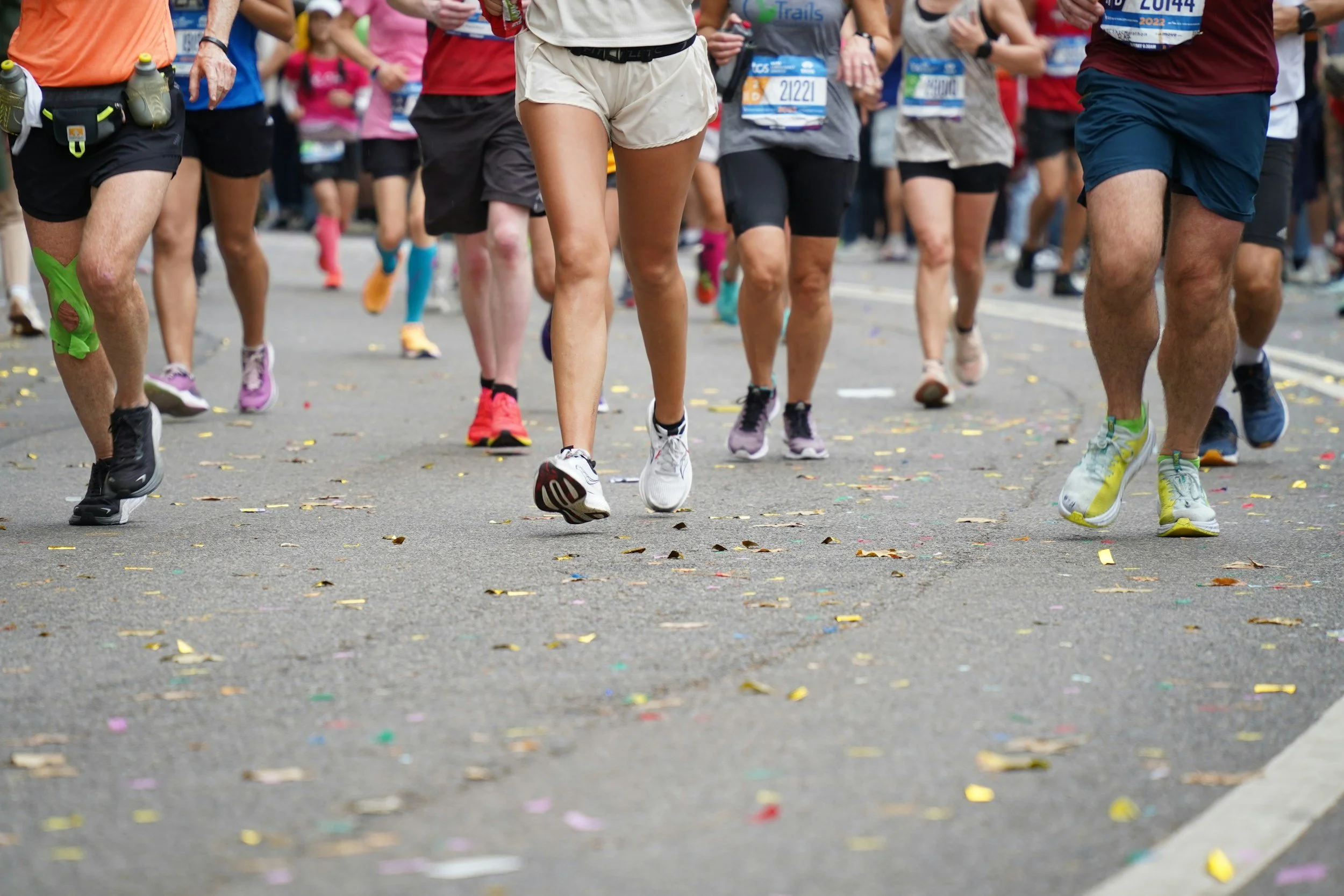 Picture of a group of runners from their waist down in an event, running along the road