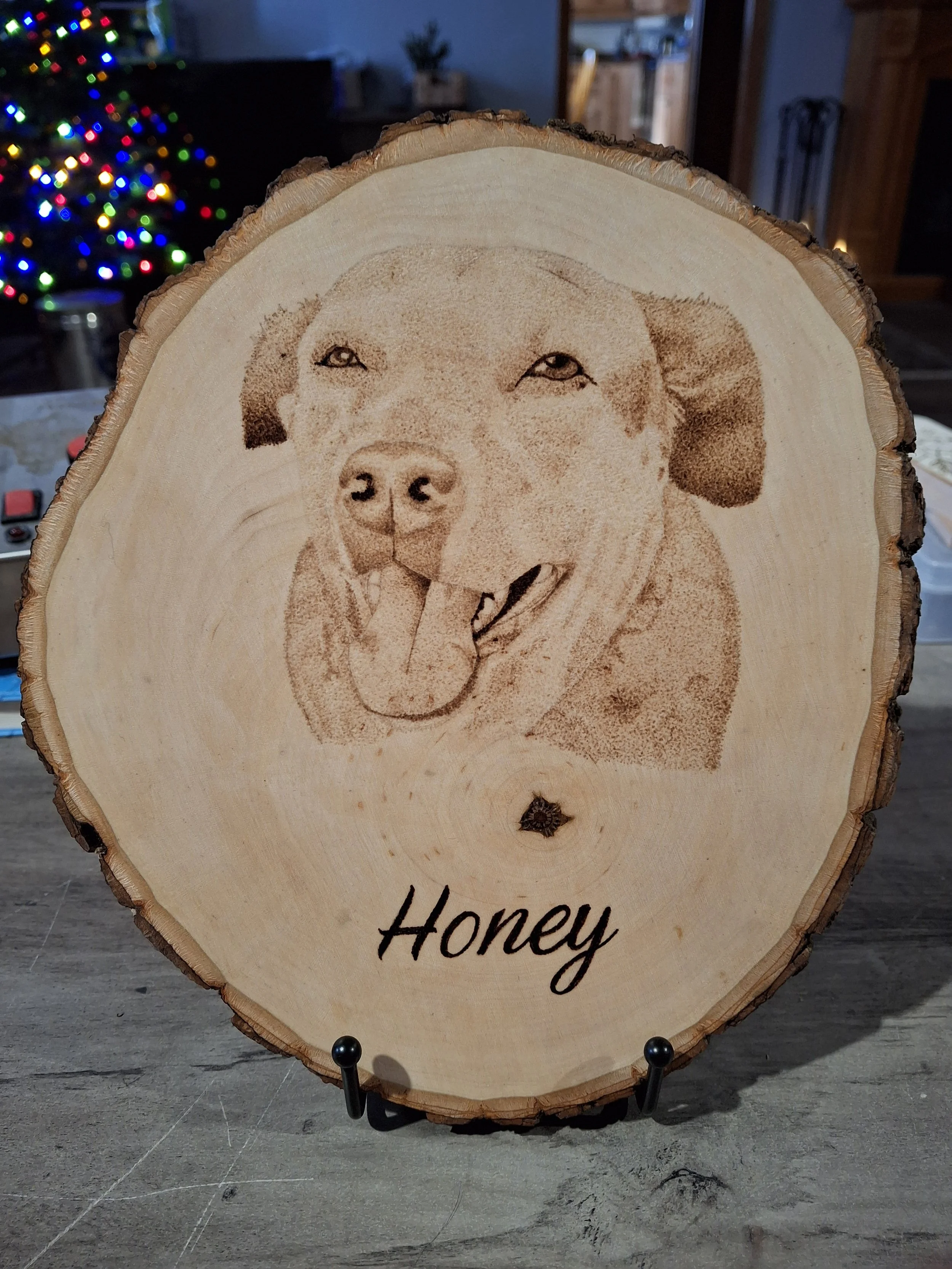 Wood cookie with a hand burned stippled image of a happy dog and the word 'Honey' written below.