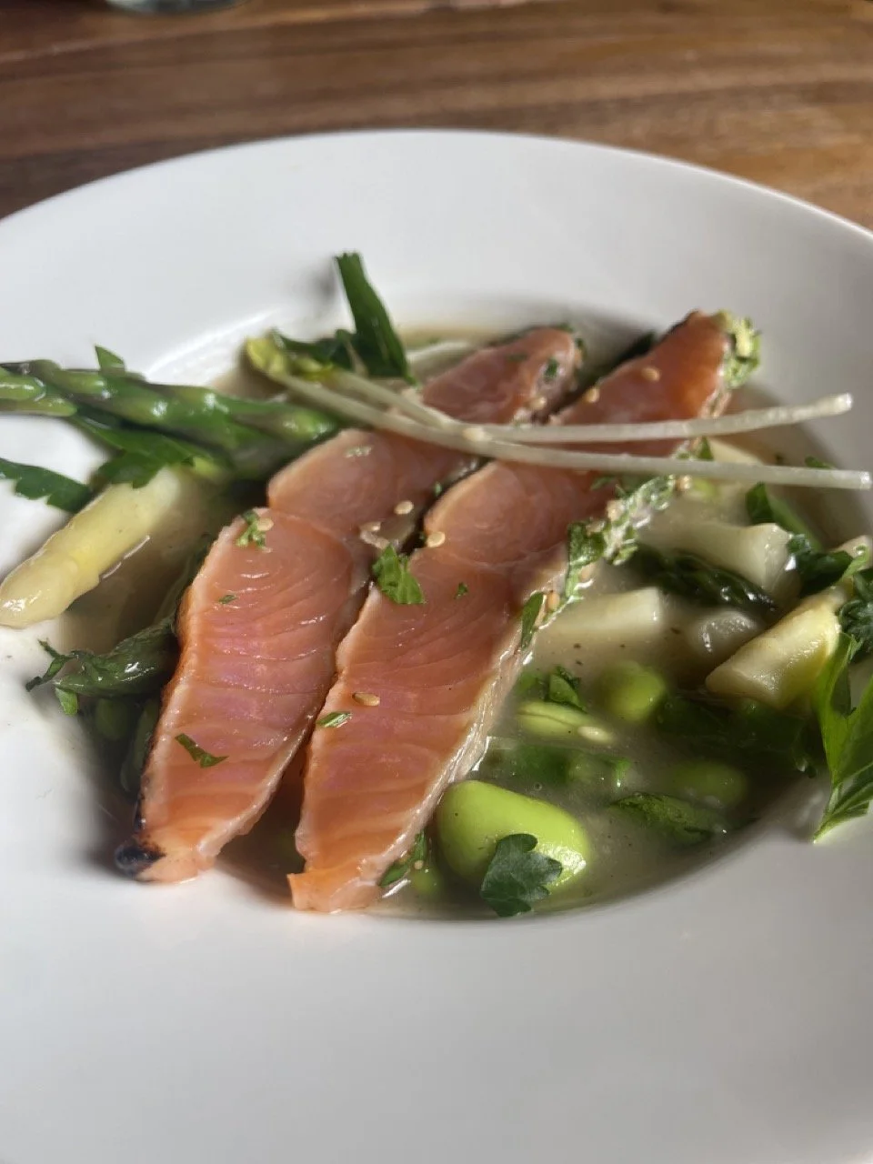 Bord met vers gerookte zalm, groene asperges, en groenten in bouillon