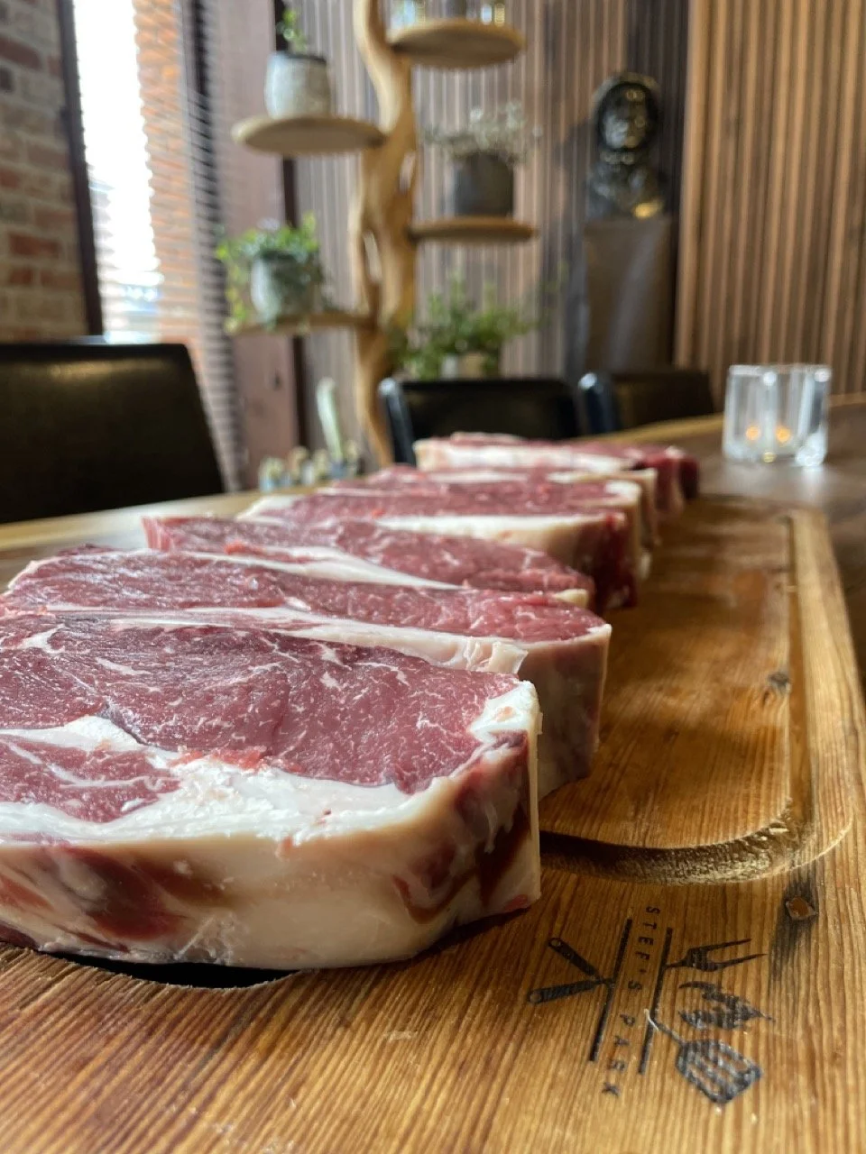 Vijf ruwe stukken rib-eye op een houten snijplank in een restaurant (Maison Jacques).