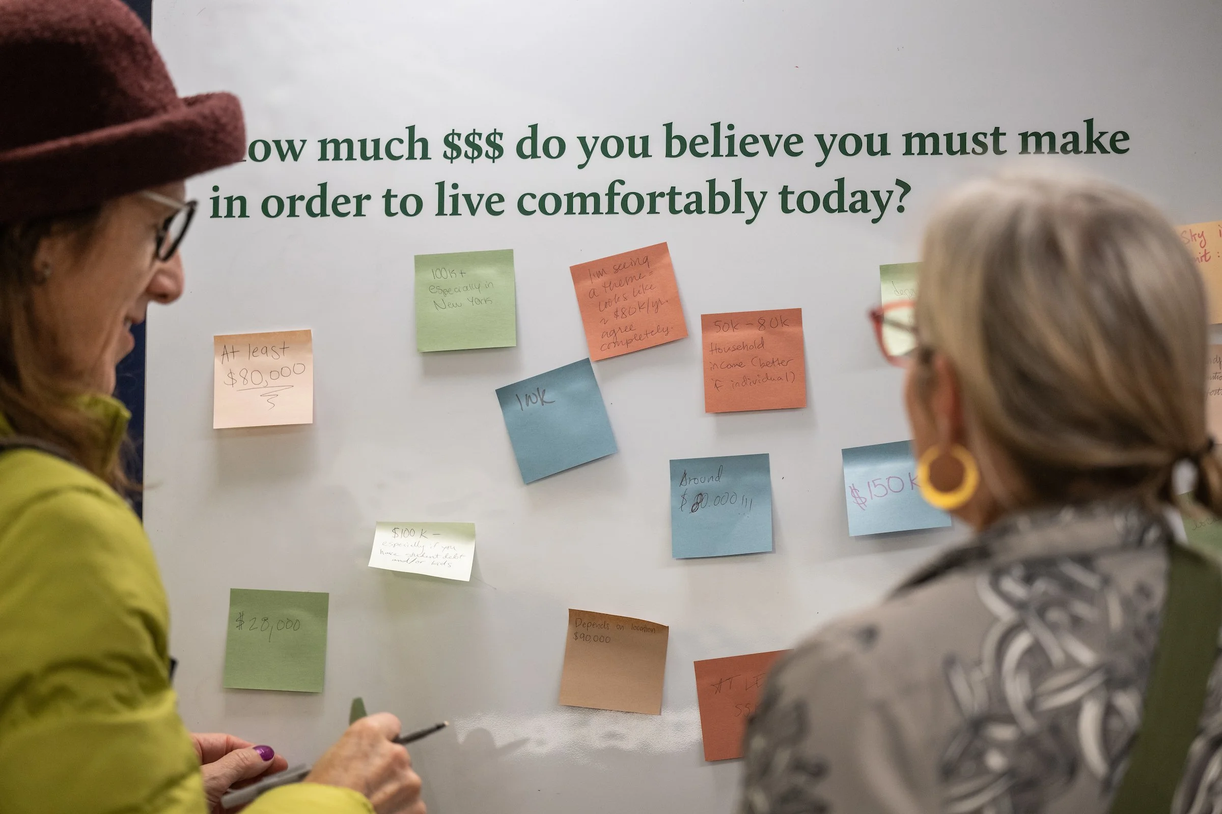 Two women look at a board with post it notes