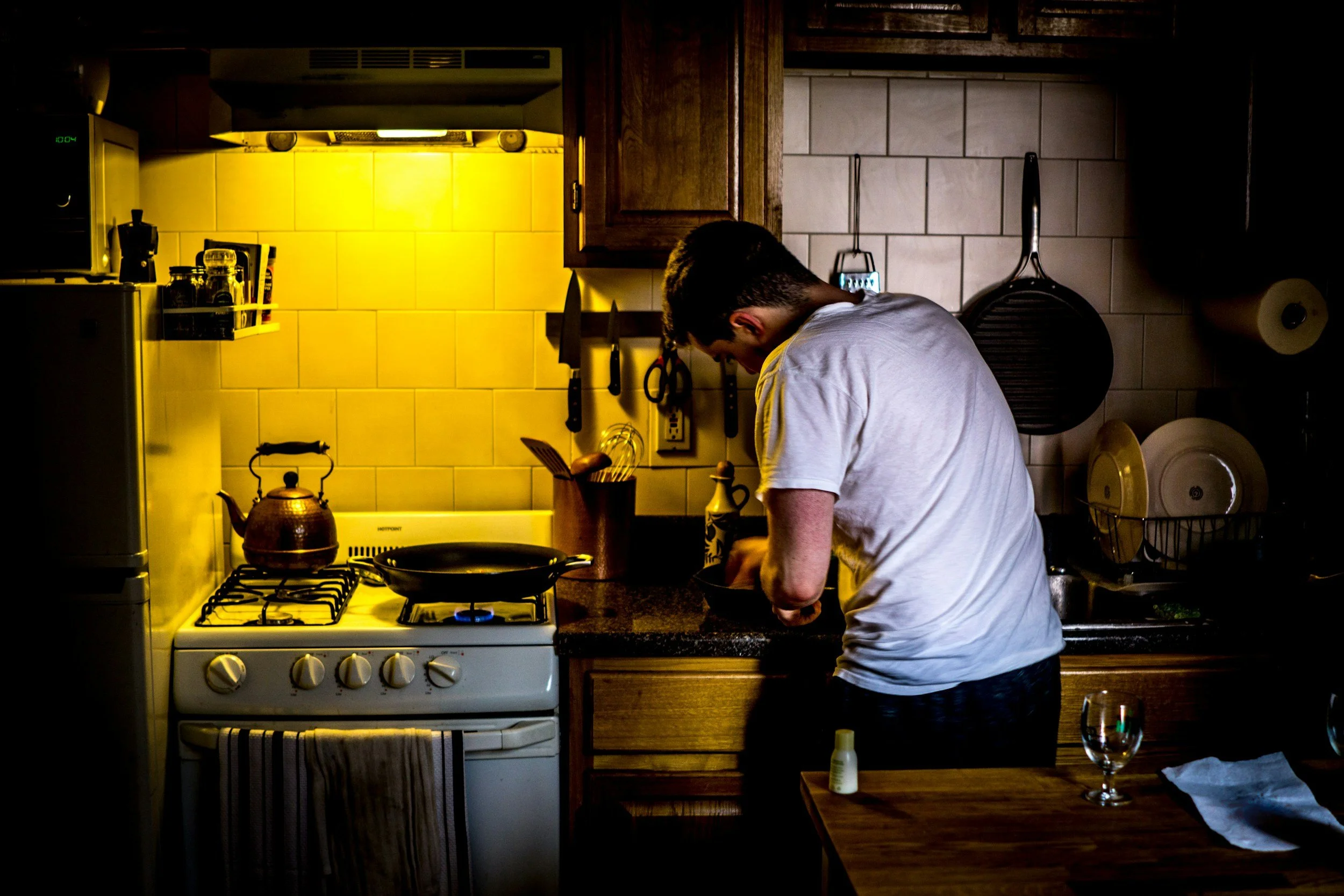 A man in a white shirt is preparing a meal in his kitchen.