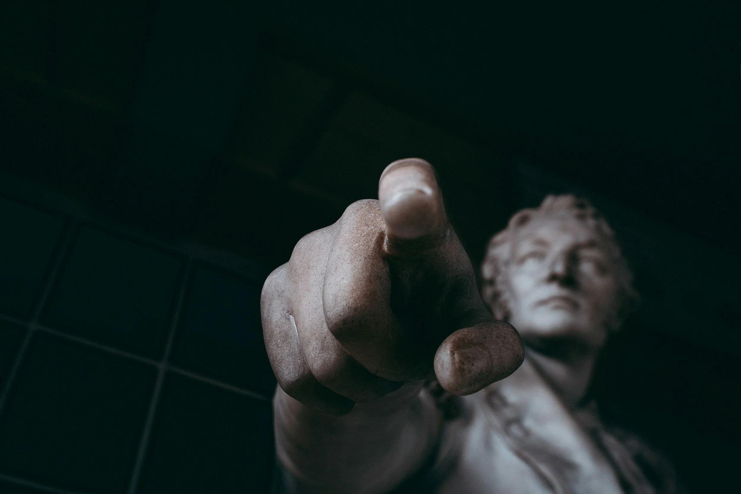 A statue of a man pointing his index finger at you.
