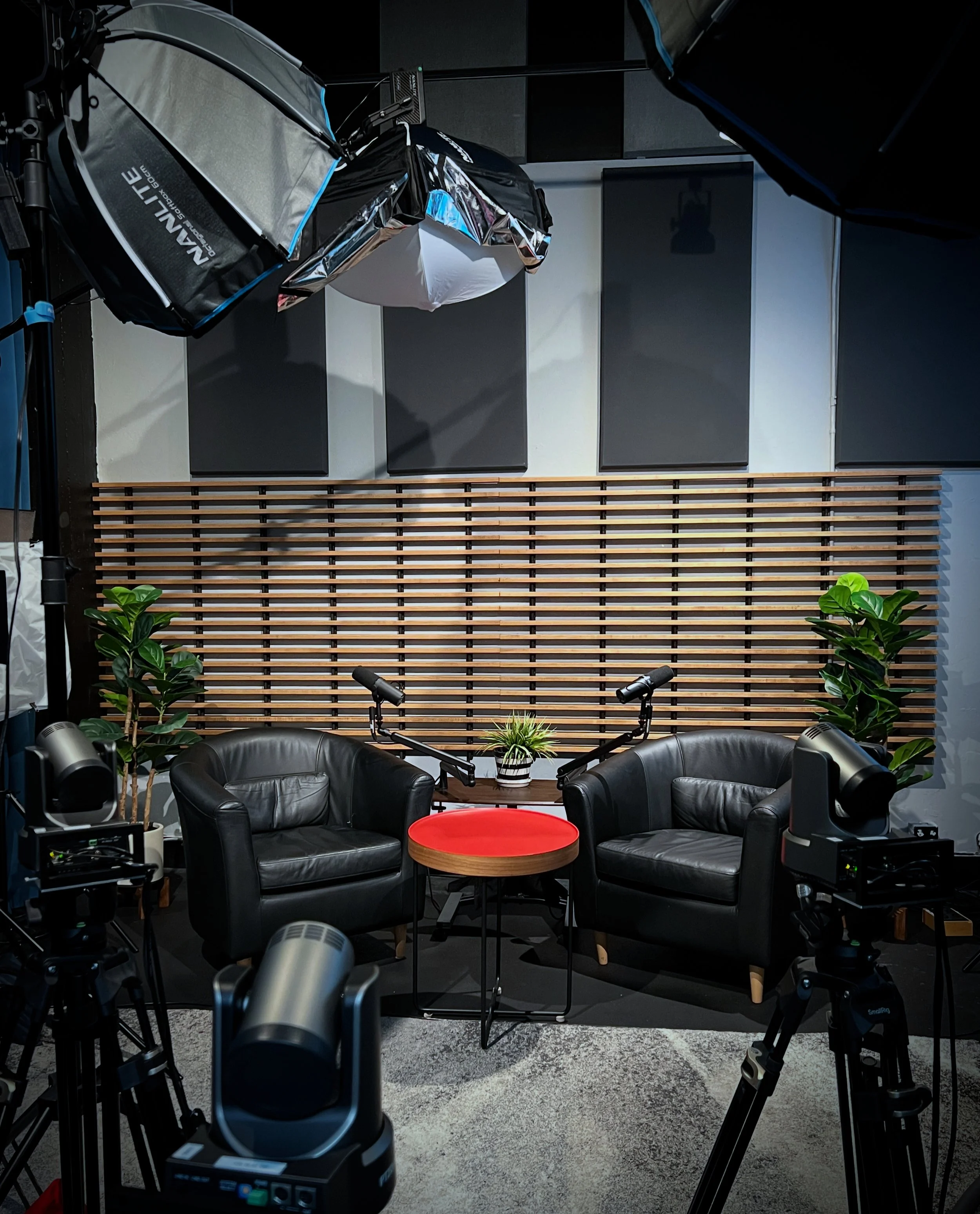Armchair podcast setup with two boom mics and bts gear