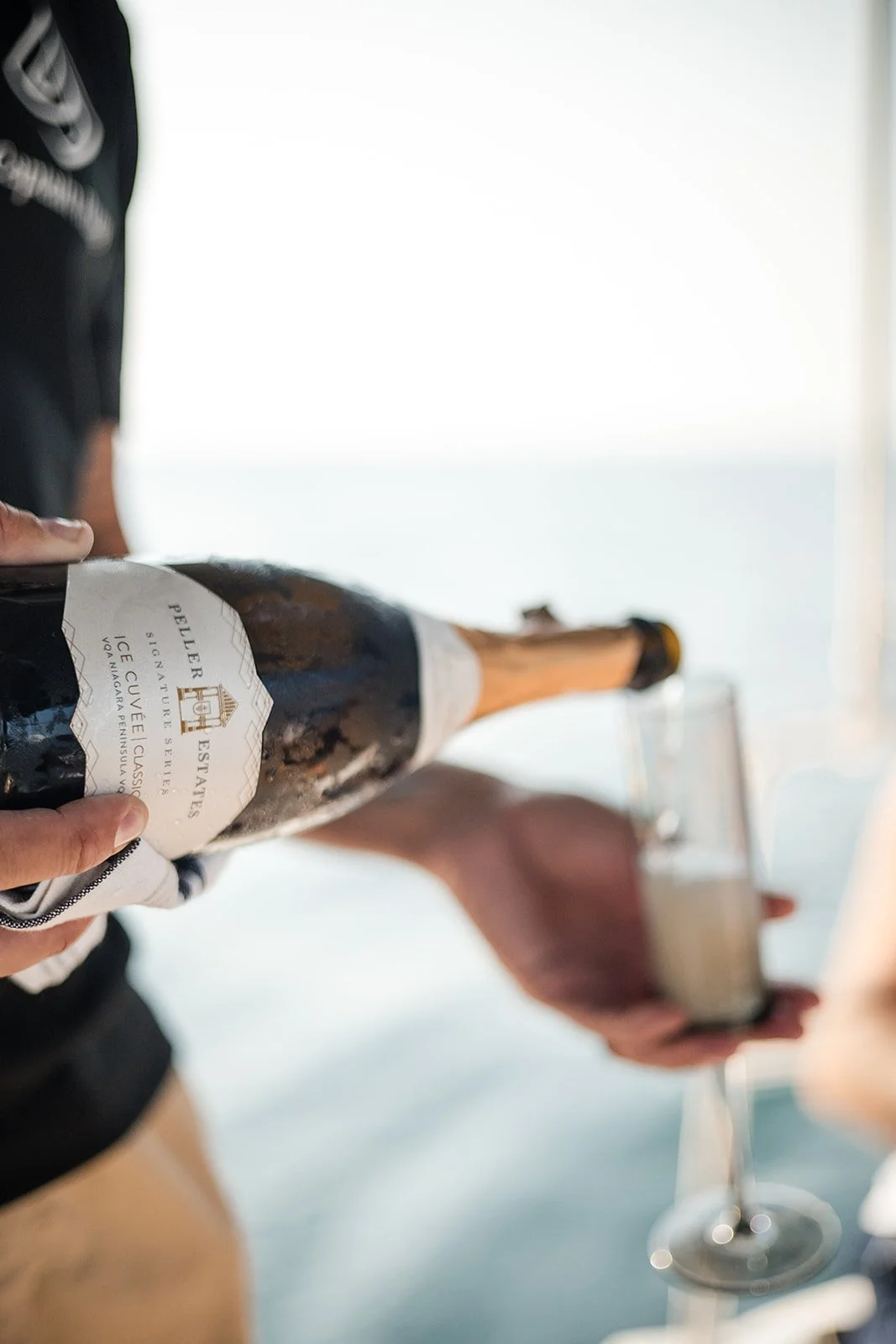 A table set for celebration on a yacht with champagne, a cake, and candles, with boats in the background.