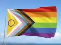 A rainbow pride flag flying against a blue sky.