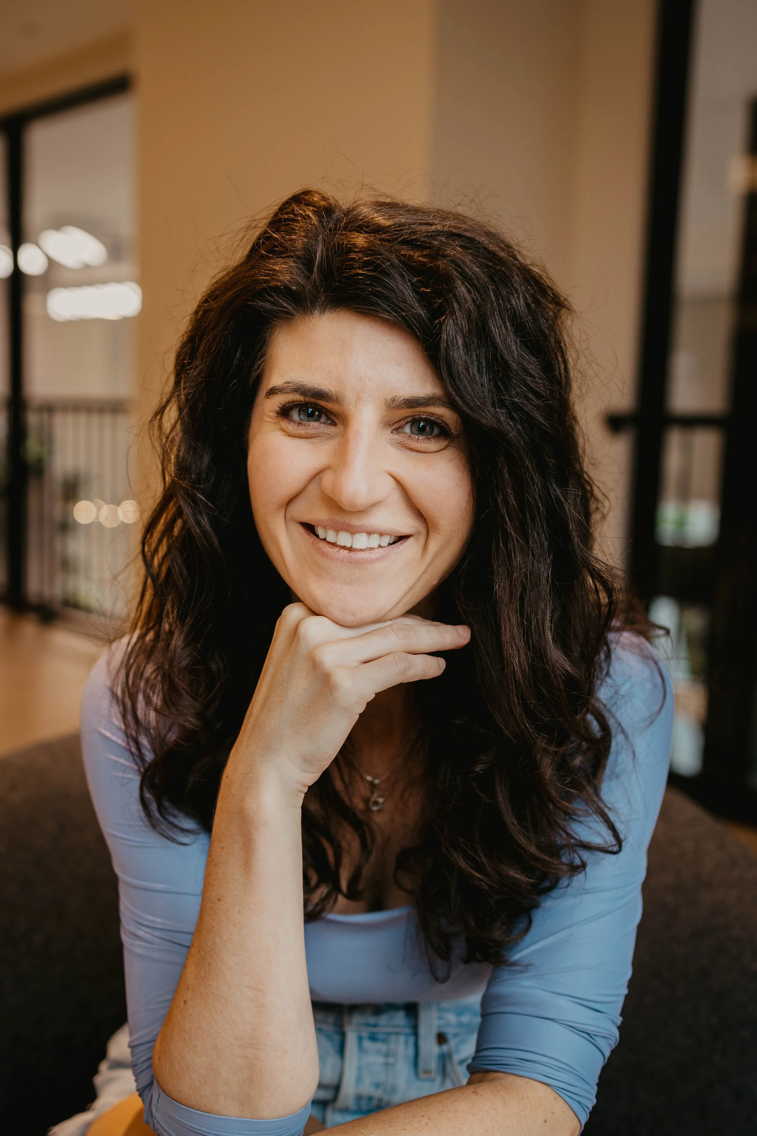 Arielle Disick, entertainment lawyer and Chief Operating Officer at Sound Logic: dark curly hair sitting indoors with her chin resting on her hand, wearing a light blue long-sleeve shirt.
