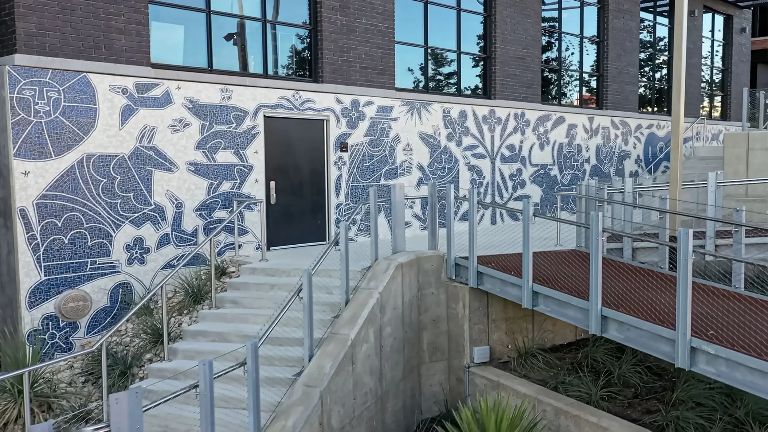 Close-up of the right section of America Martin's "Armadillo's Song" at Centro, East Austin, TX. The hand-cut Otomi mosaic mural in blue and white showcases the Colombian-American artist's bold figurative forms including a sun face, animals, figures,