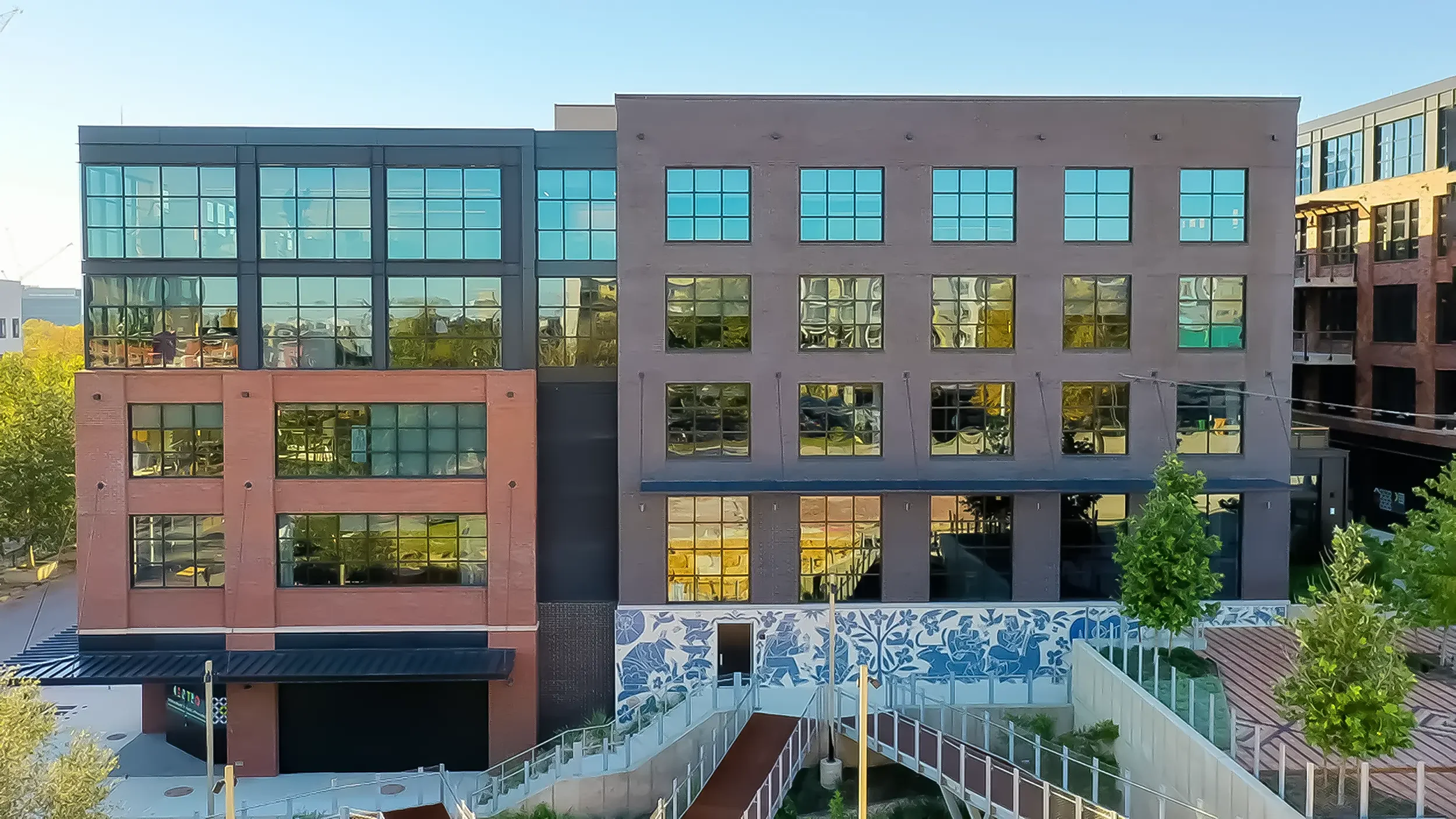 Aerial daytime view of America Martin's 70-foot hand-cut Otomi mosaic mural "Armadillo's Song" at Centro mixed-use development in East Austin, TX. The Colombian-American artist's blue and white public art installation spans the exterior courtyard wal