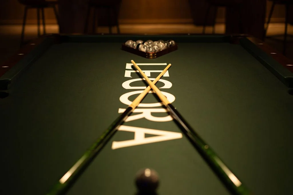 Legora branding on a green pool table with crossed pool cues.