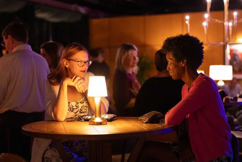 Guests talking at a candlelit table during the Legora event.