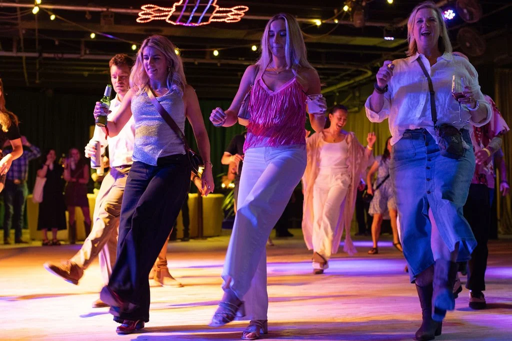 Guests line dancing together on the event dance floor.