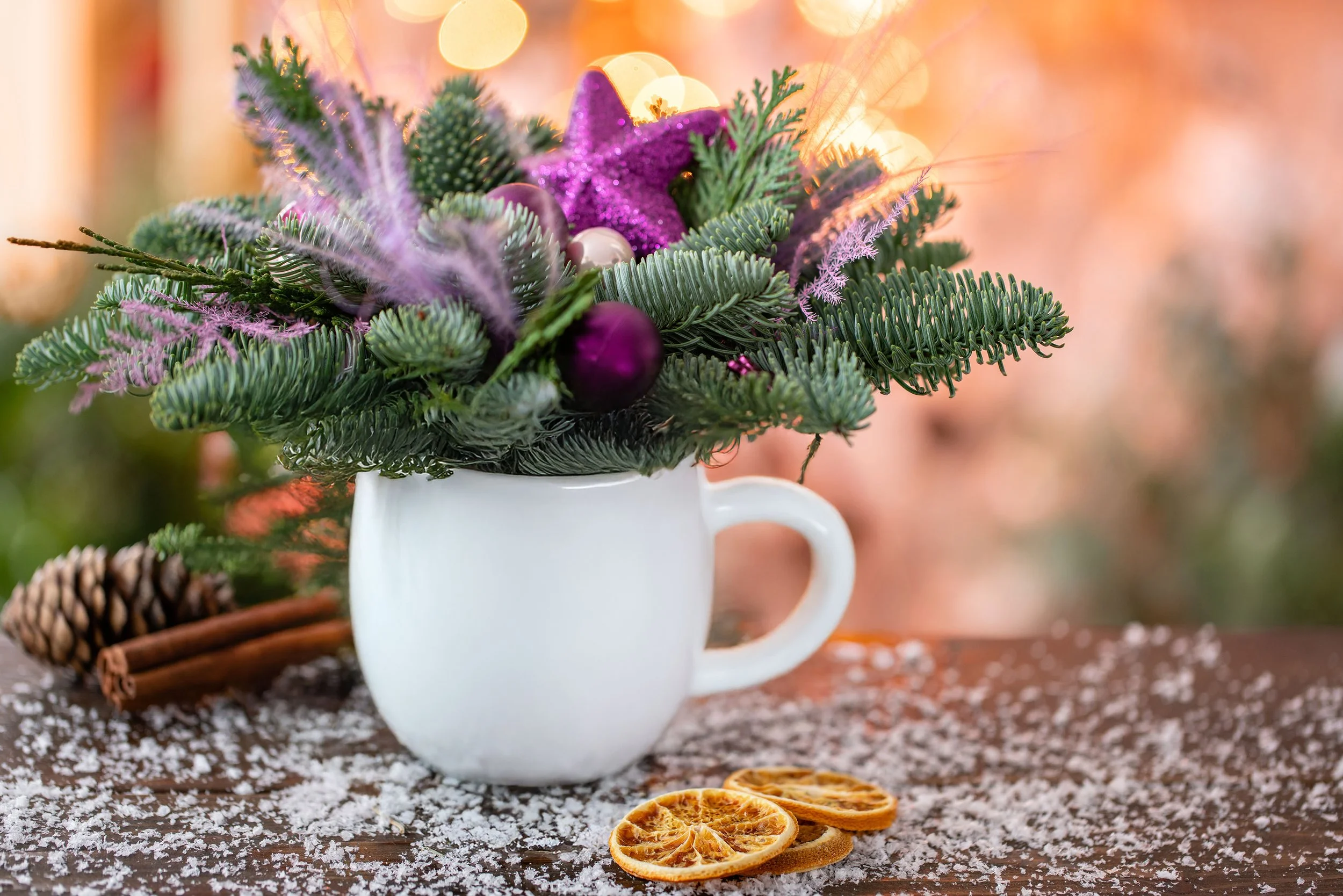 Christmas floral arrangement in a white mug, featuring evergreen branches and holiday accents.