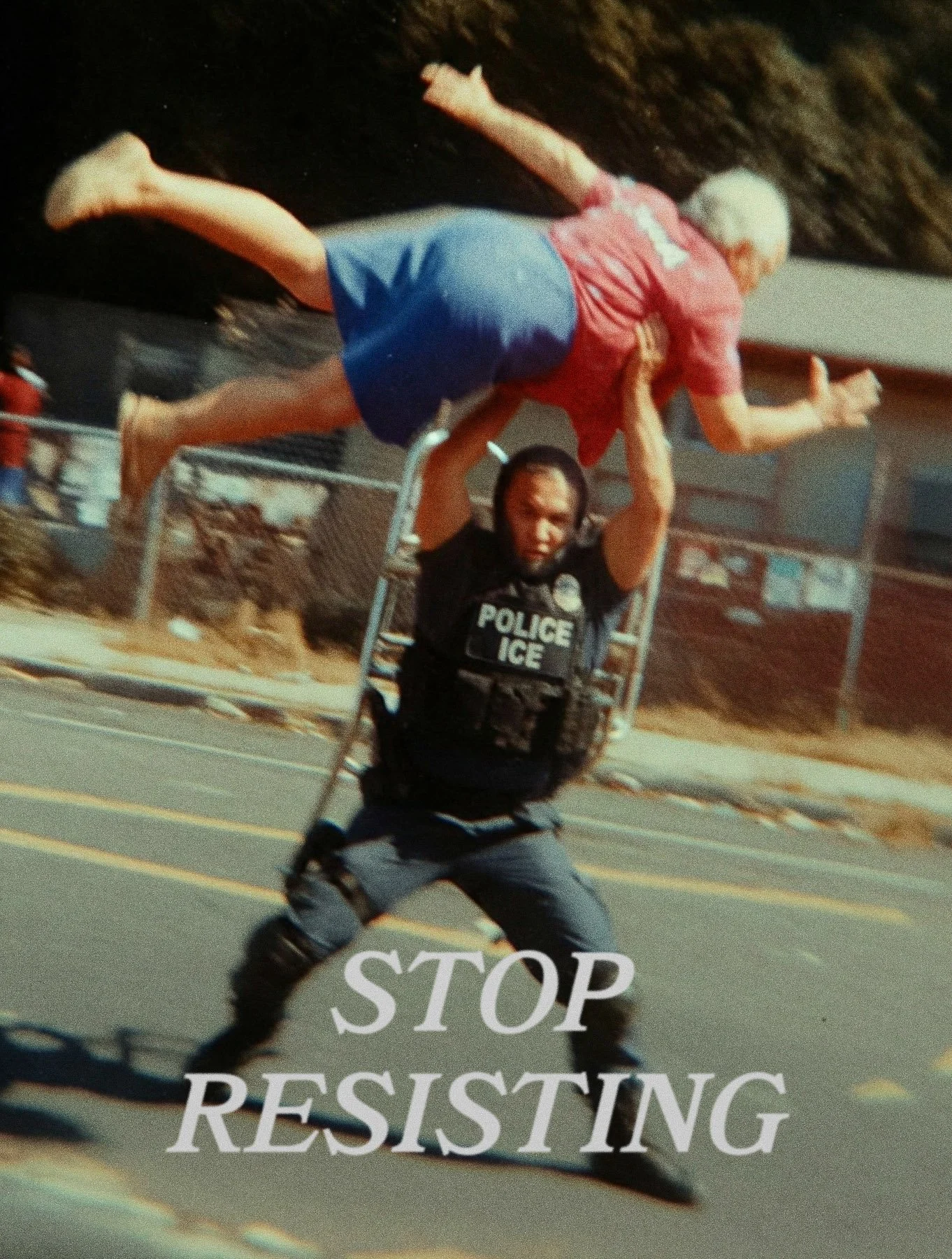 A police officer in tactical gear and motorcycle boots raises a metal barrier with the words "STOP RESISTING" written on it in front of a person being lifted over the barrier during a protest or riot.