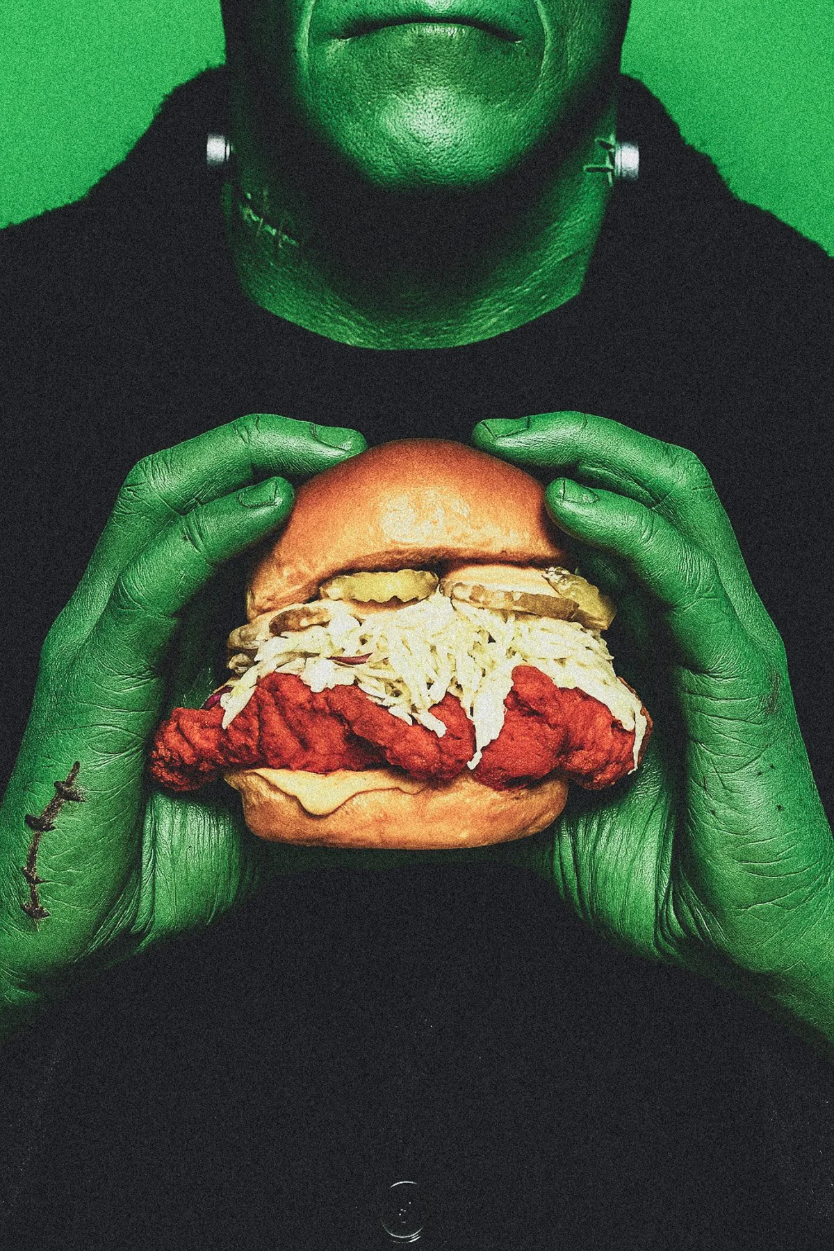 Person with green skin holding a burger with fried chicken, coleslaw, and pickles, against a green background