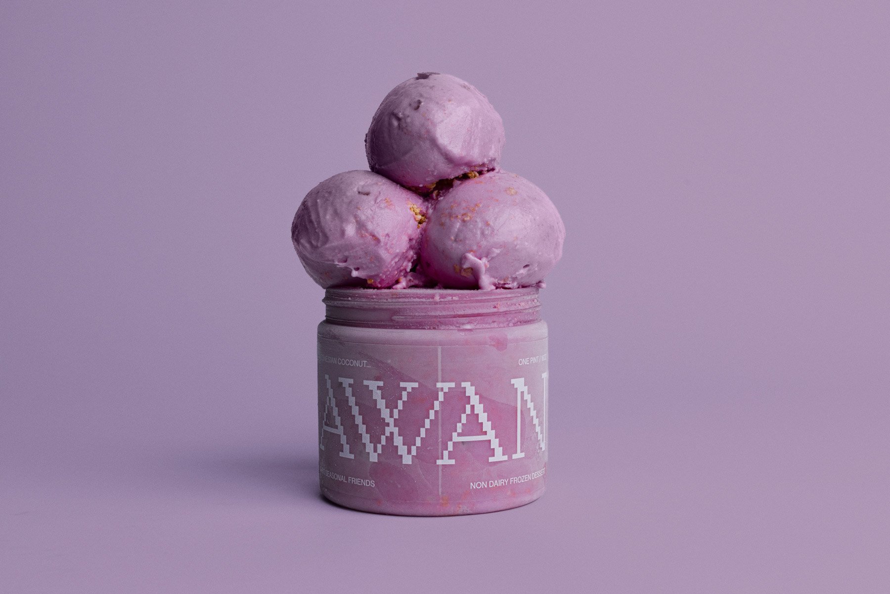 Pink container of ice cream with three scoops on top, set against a lavender background.