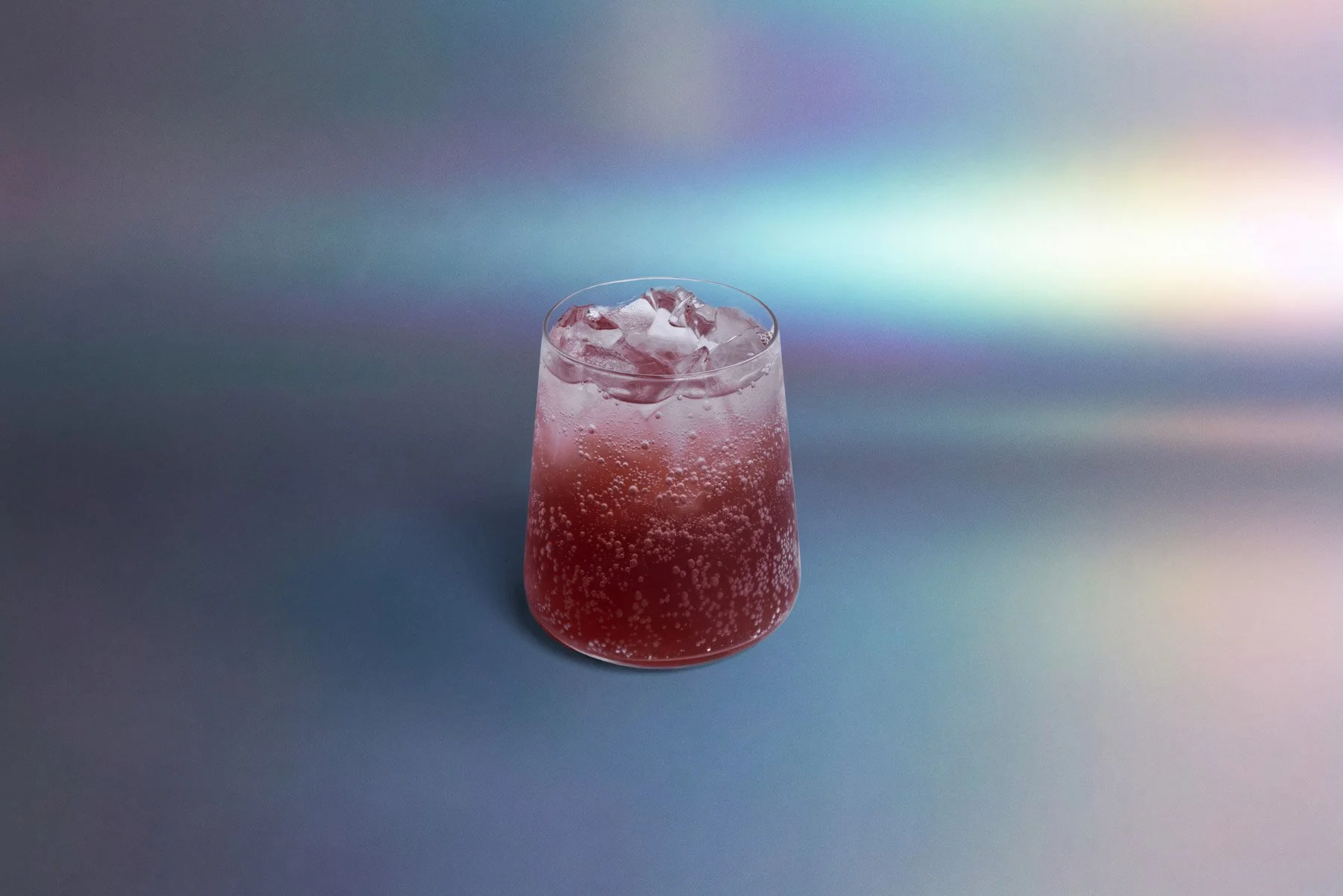 A clear glass filled with a pink, sparkling drink and ice cubes on top, set against a gradient holographic background.
