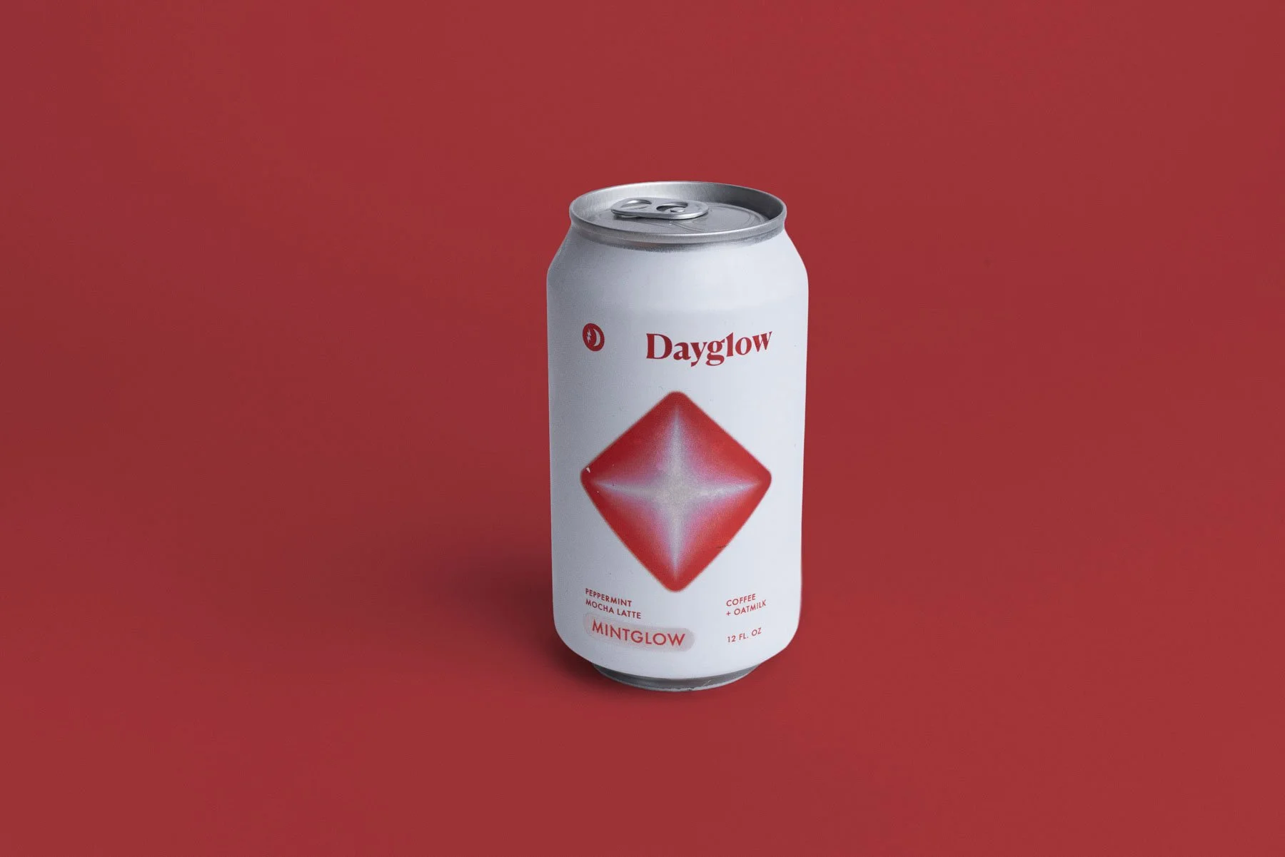A white can of Dayglow MintGlow, a peppermint mocha latte with coffee and oat milk, standing on a red background.