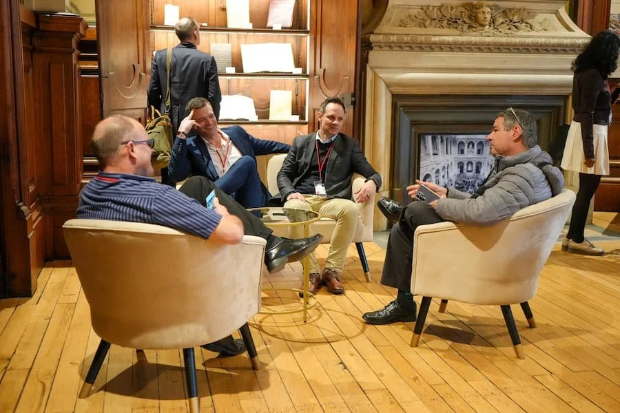 2025 in review - men sitting in chairs around a coffee table in front of a fireplace