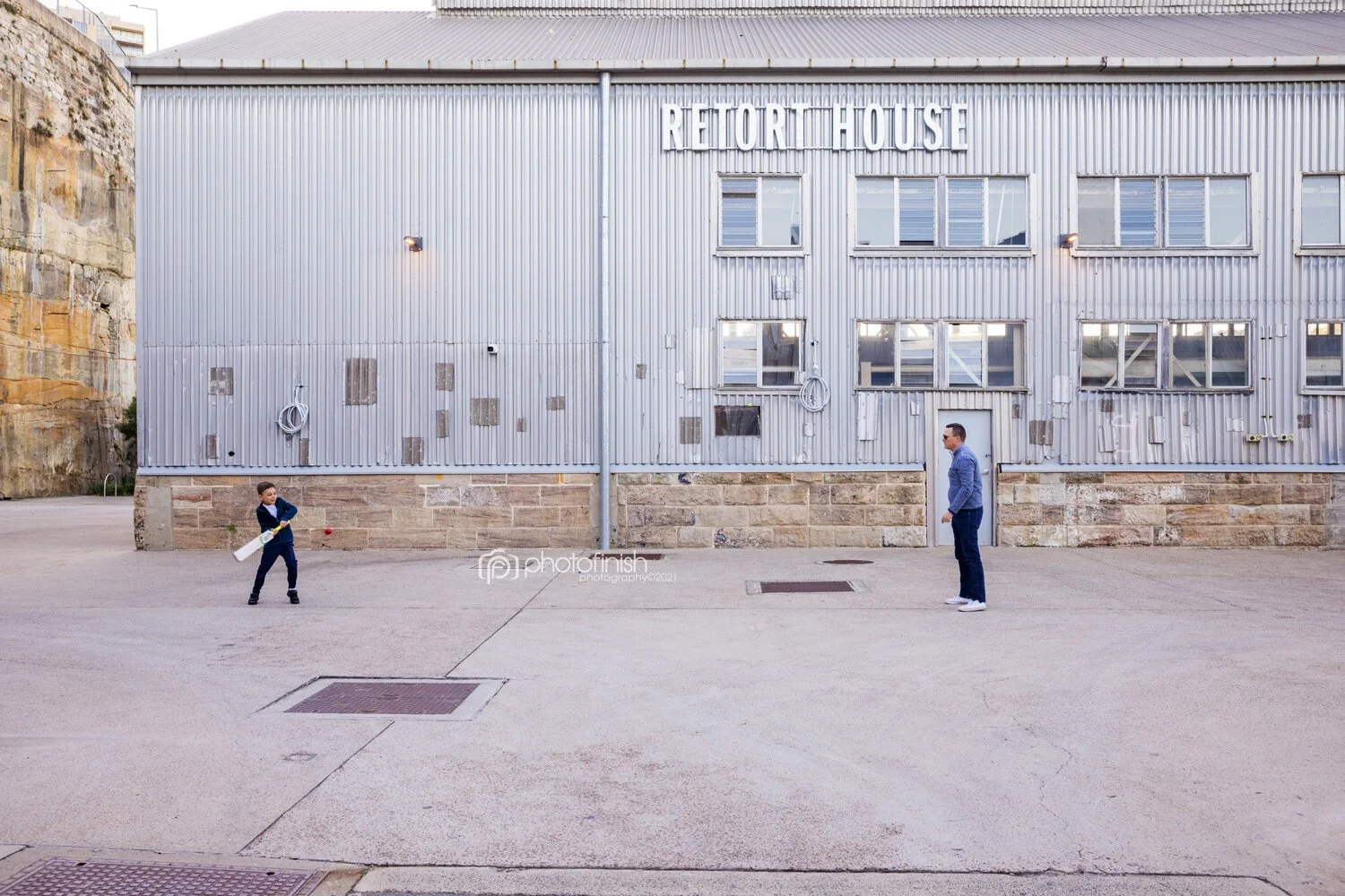 Father and son playing cricket outside the Retort House at Sub Platypus Base in North Sydney during family photo session