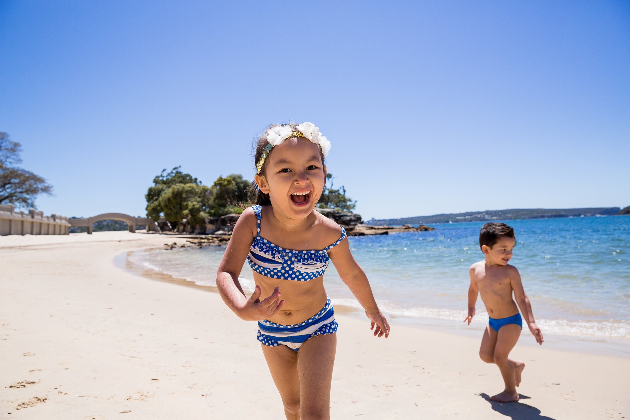 children playing and laughing during a candid beach photo session at Balmoral Beach, Sydney, with natural light and relaxed expressions