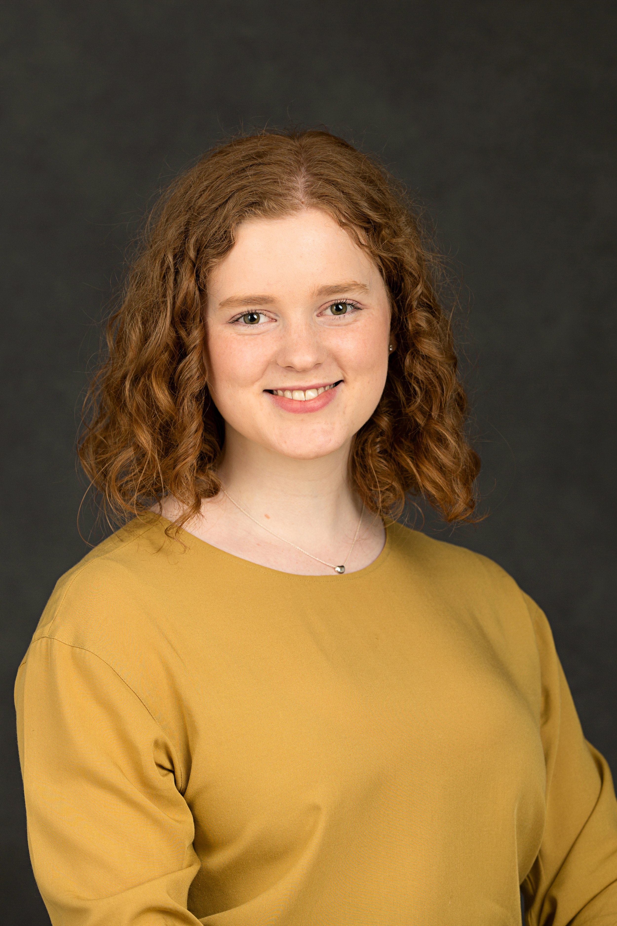 Professional headshot of female university student in mustard sweater for music education