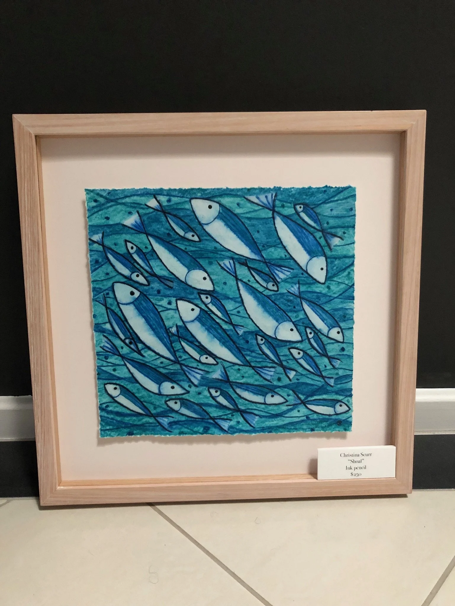 Framed artwork titled "Shoal" by Christina Stern, created with ink and pencil, depicting a school of blue and white fish swimming in bluish water.