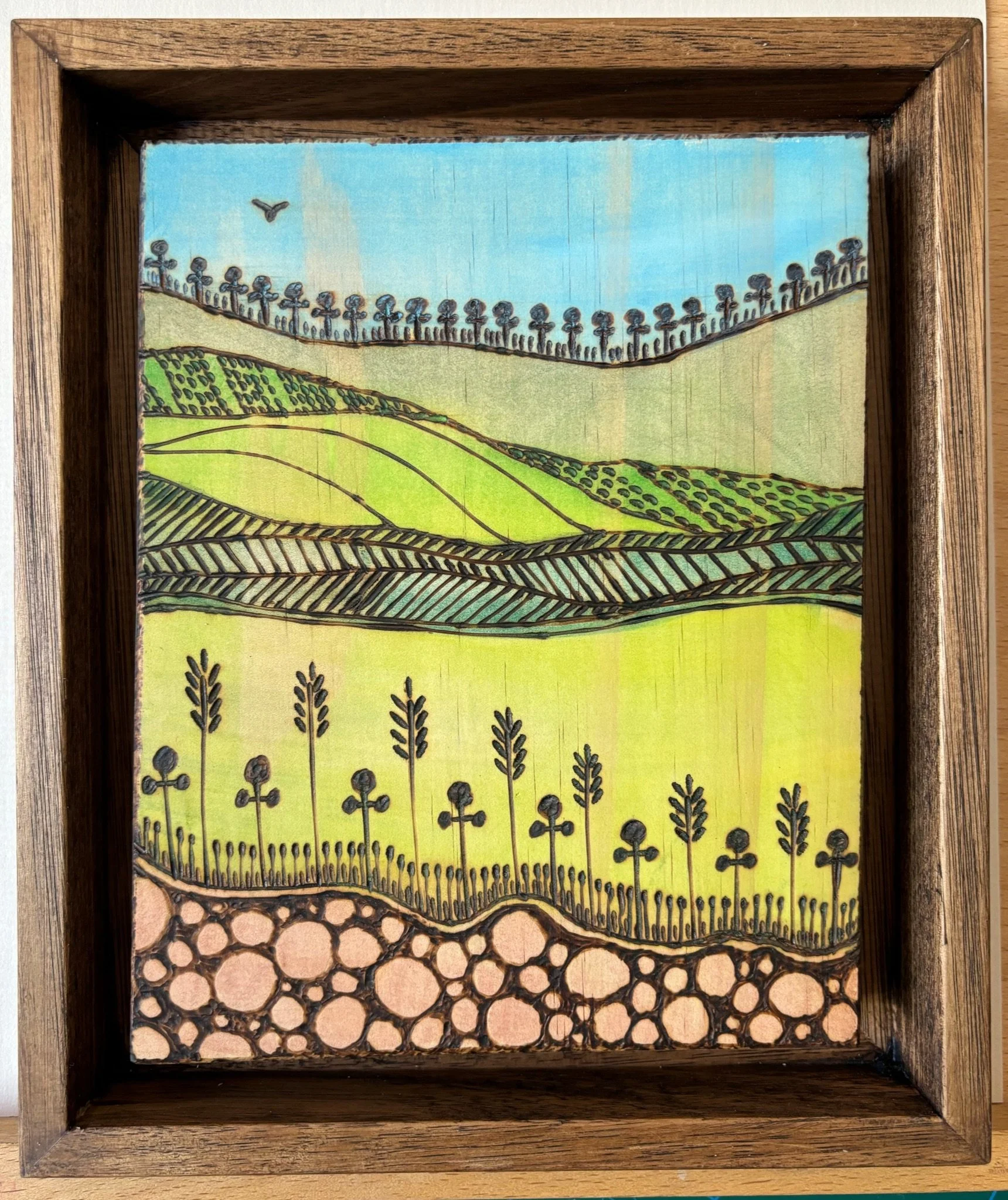 Illustration of rolling hills, farmland, and crops, with a bird flying in the sky.