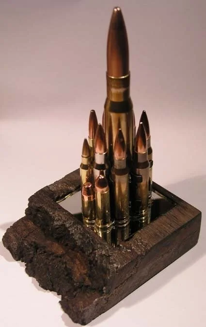 A wooden display resembling a small fortress with rifle cartridges arranged as turrets in a square formation.