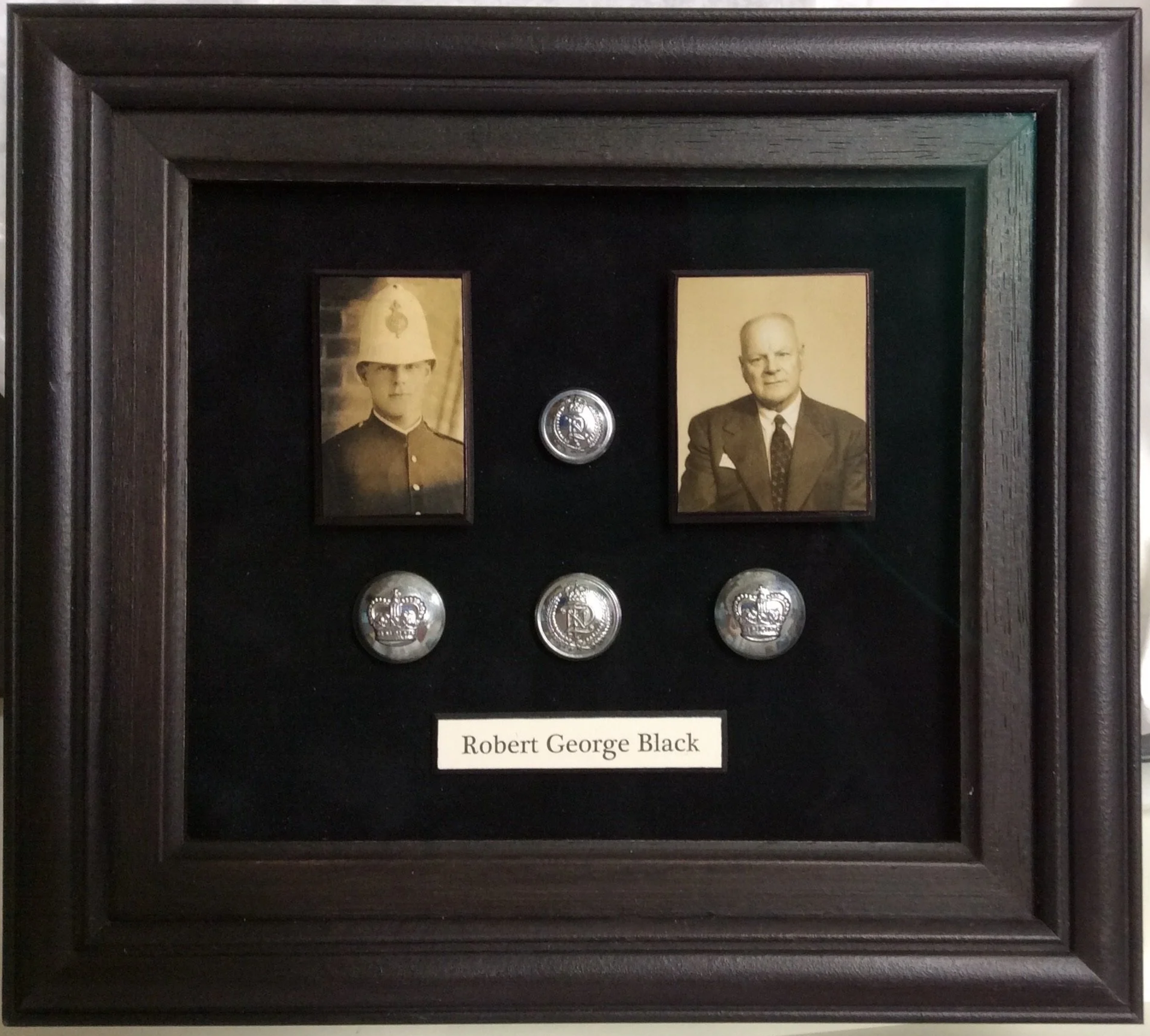 Framed display with two black-and-white photos, three silver badges, and a nameplate reading 'Robert George Black' inside a wooden frame.
