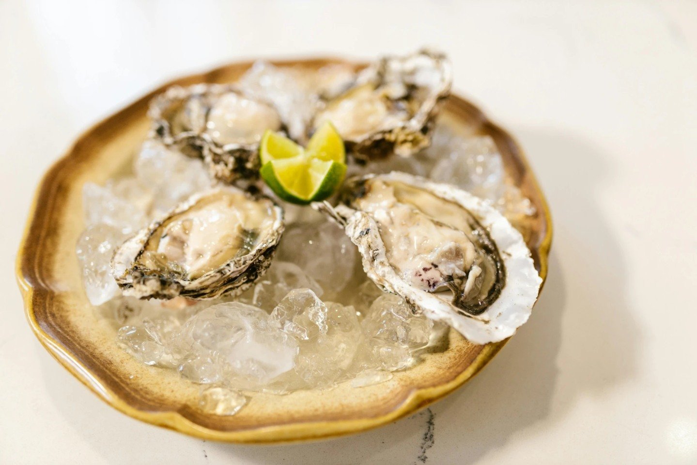 Elevate your dining experience with oysters on a golden plate! 🌟🍽️✨ The shimmering backdrop accentuates the briny treasures nestled within, creating a feast fit for royalty. Indulge in the luxurious combination of golden opulence and oceanic deligh
