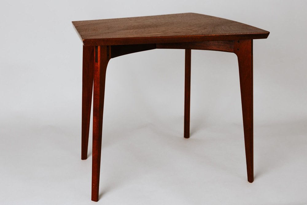 Mid-century modern wooden side table with a triangular top and tapered legs.