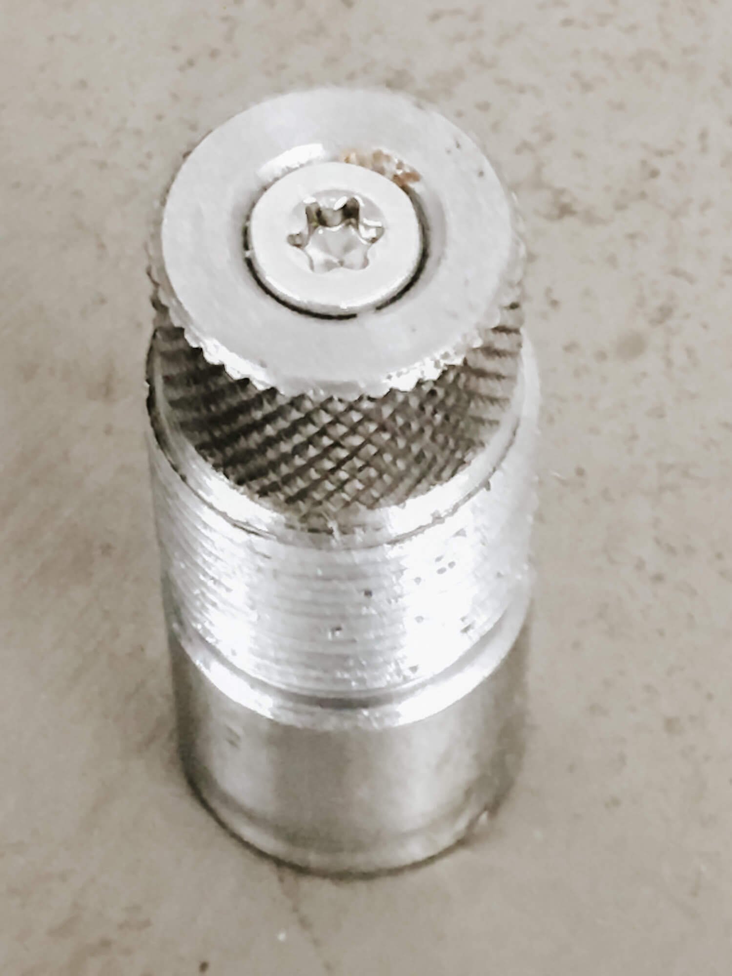 Close-up of a metal screw with a knurled surface and star-shaped drive