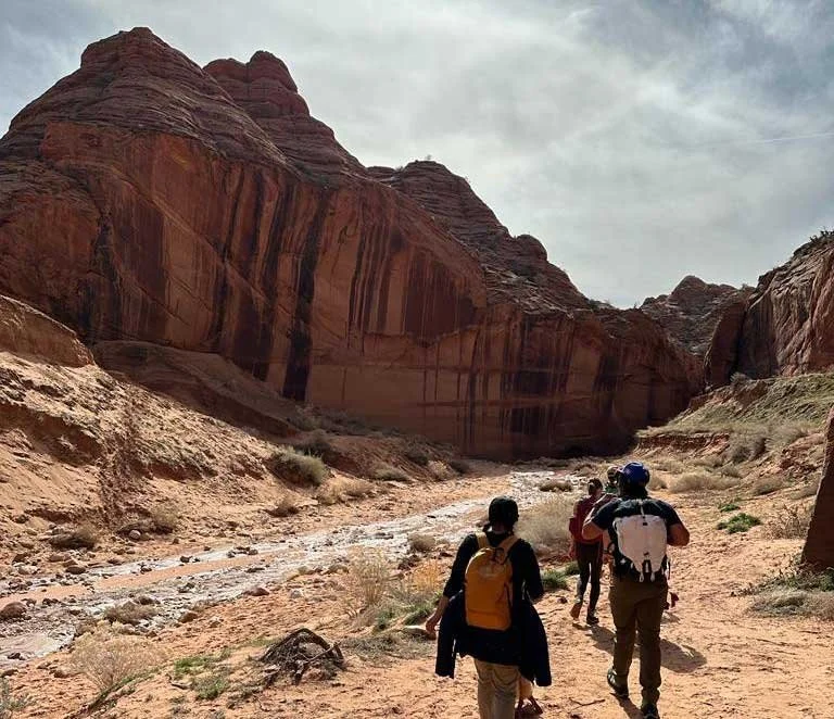 Group hiking through a rocky canyon with red sandstone formations