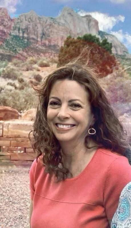 Woman smiling with scenic mountain landscape in the background.